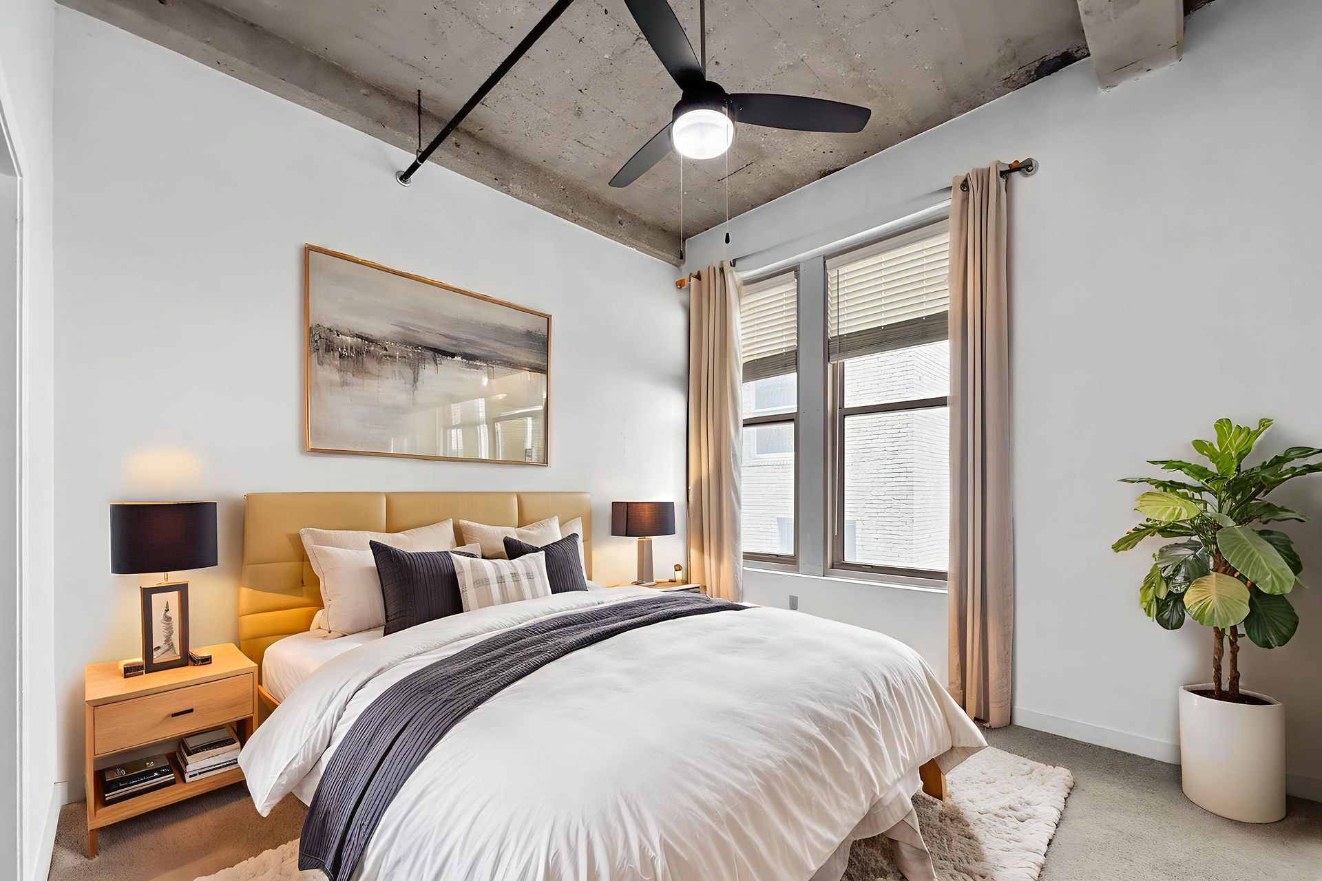 A modern bedroom featuring a bed with white bedding, a yellow headboard, two nightstands, a ceiling fan, and a potted plant.
