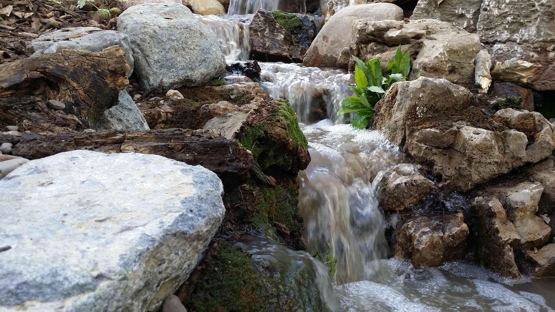 A small waterfall is surrounded by rocks and moss.
