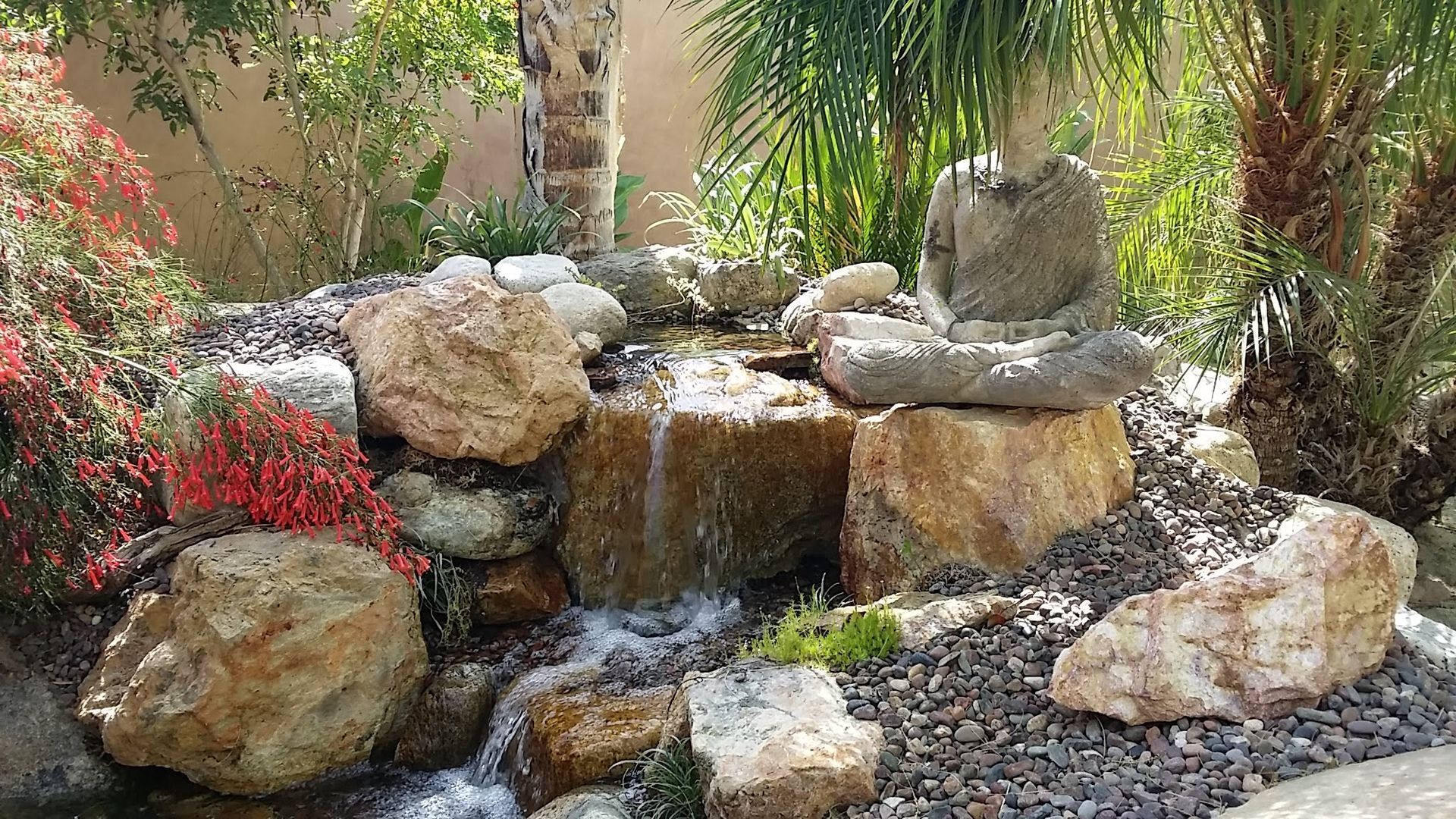 A waterfall is surrounded by rocks and trees in a garden.