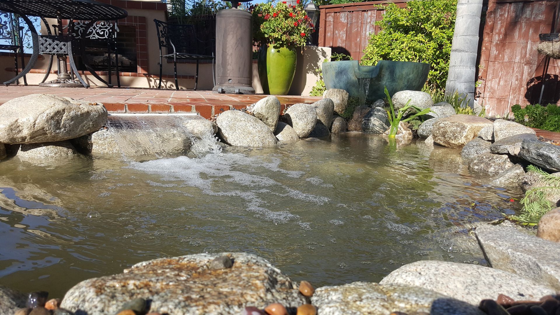 A pond surrounded by rocks and plants in a backyard