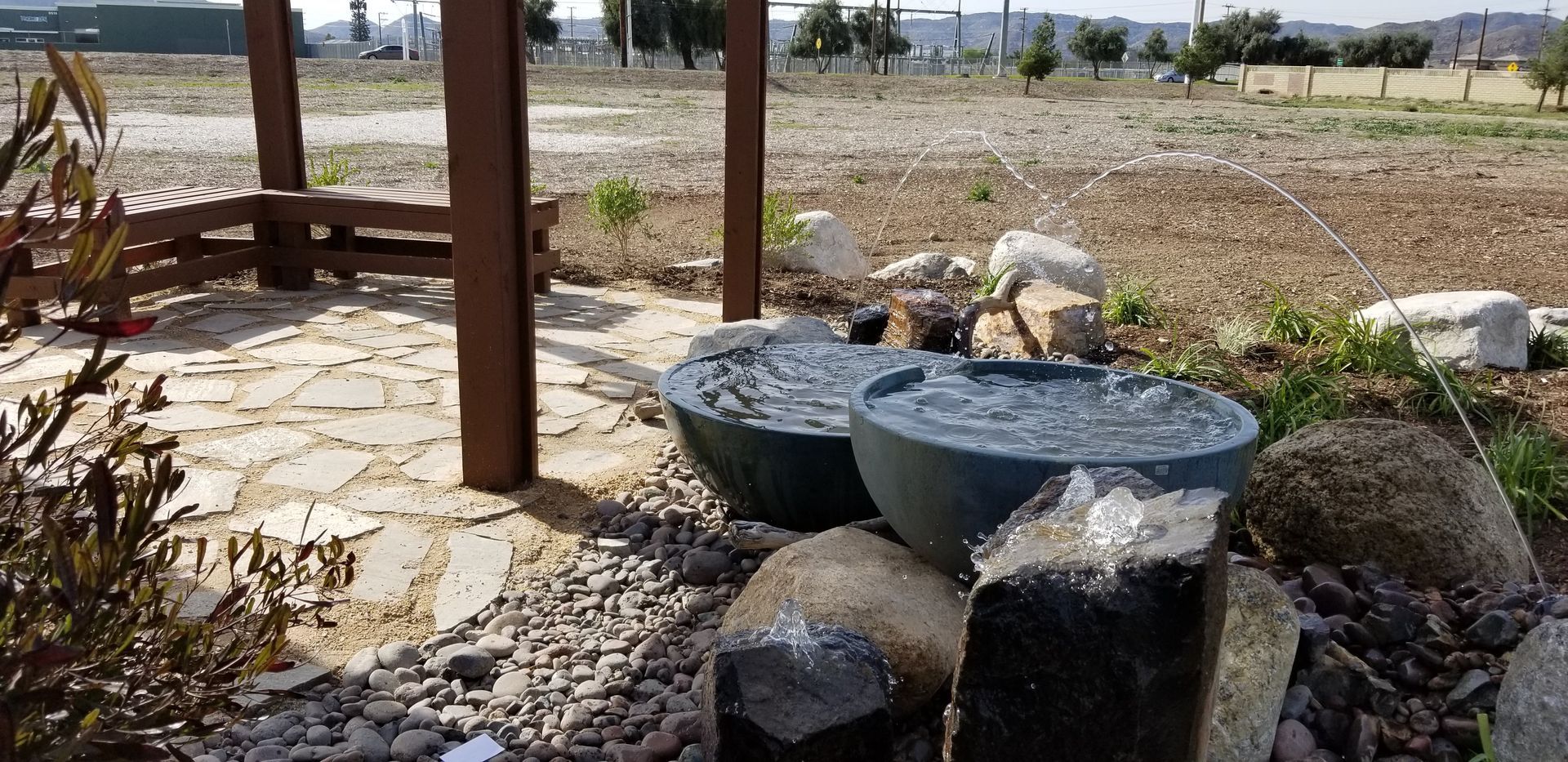 There is a fountain in the middle of a rocky area.