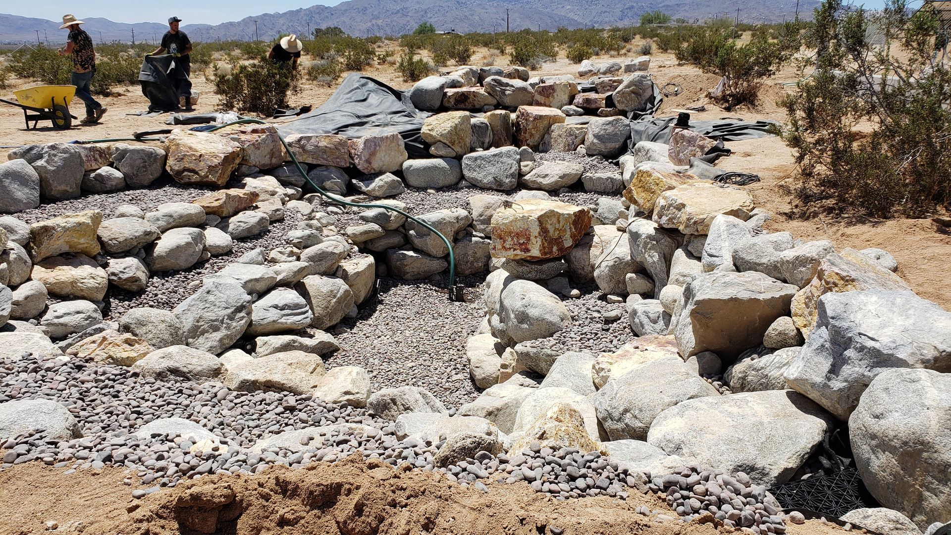A group of people are working on a rock wall in the desert.