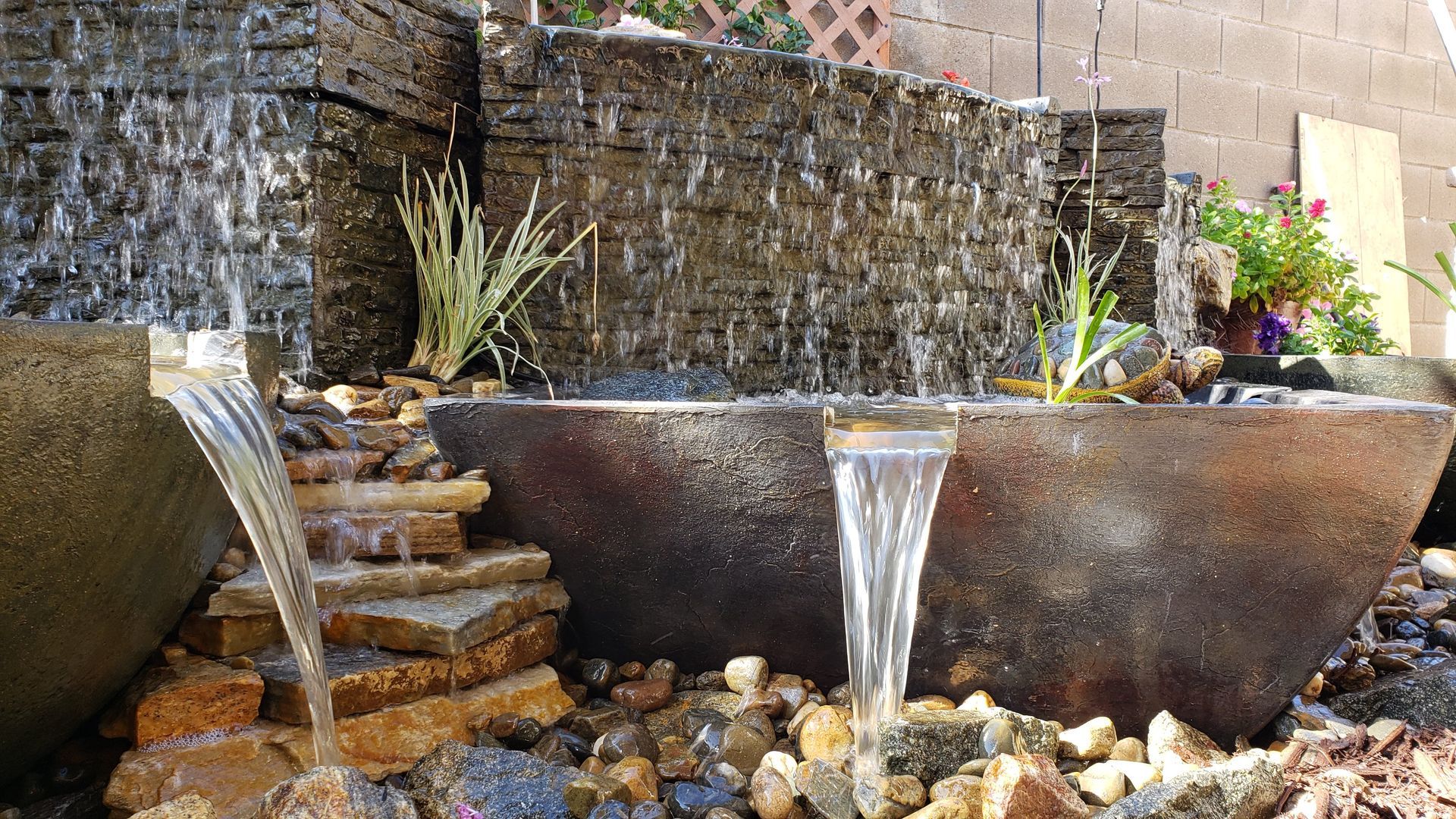 A waterfall is surrounded by rocks and plants in a garden.