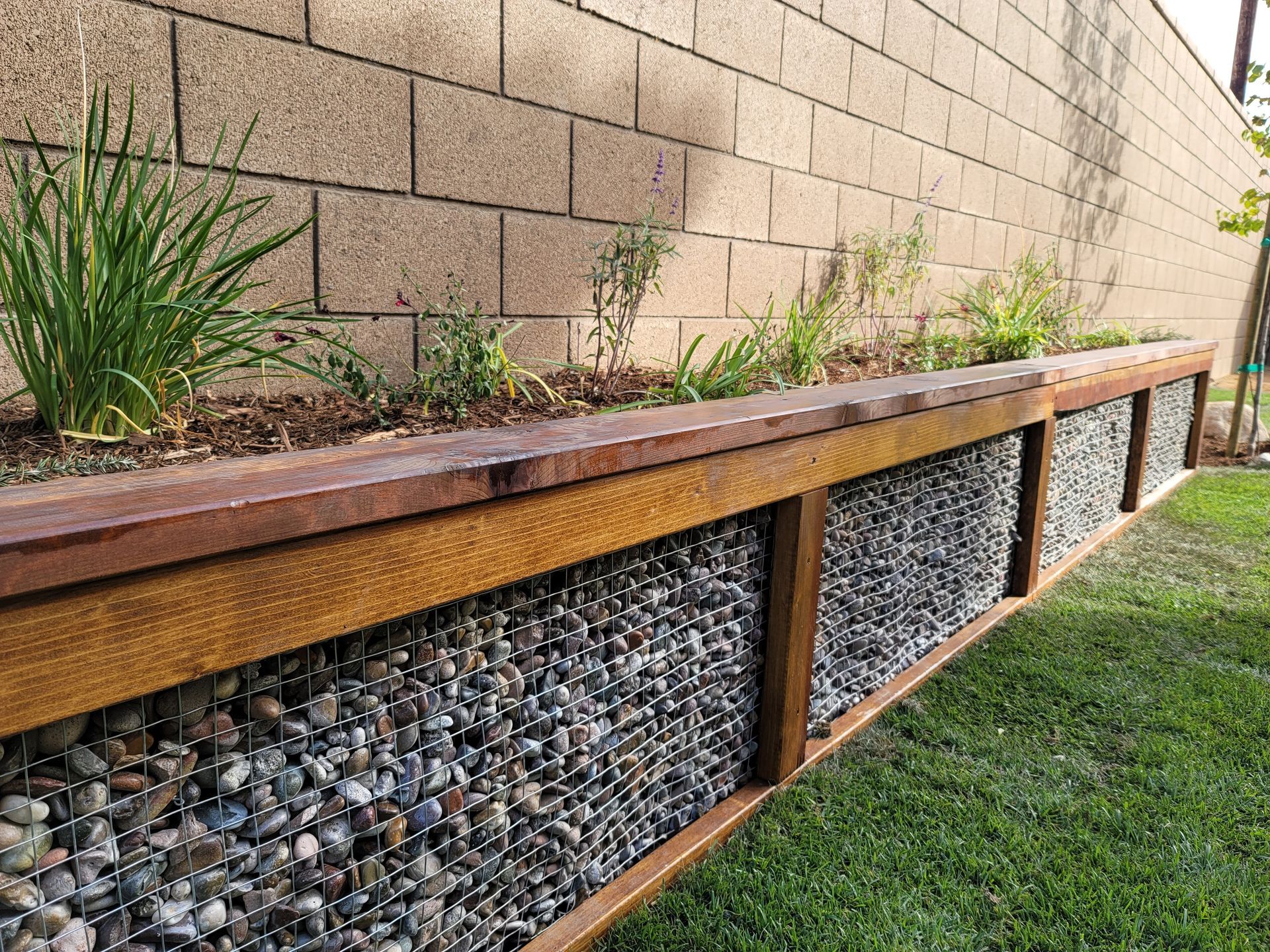 A brick wall with a wooden planter in front of it.