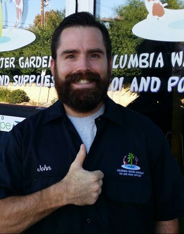 Man with a full beard giving a thumbs up in front of a water garden store.