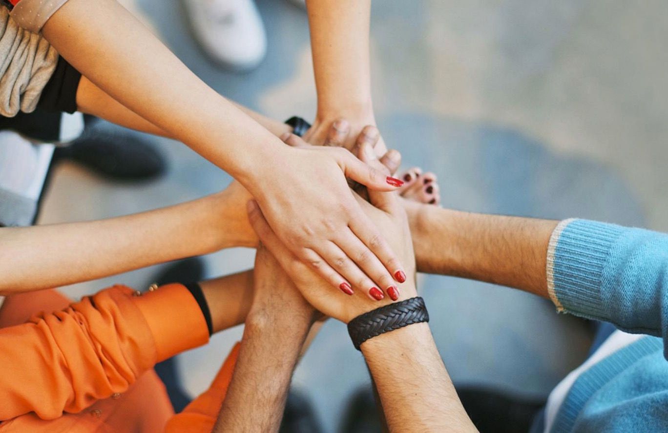 Group of hands huddled together symbolizing support