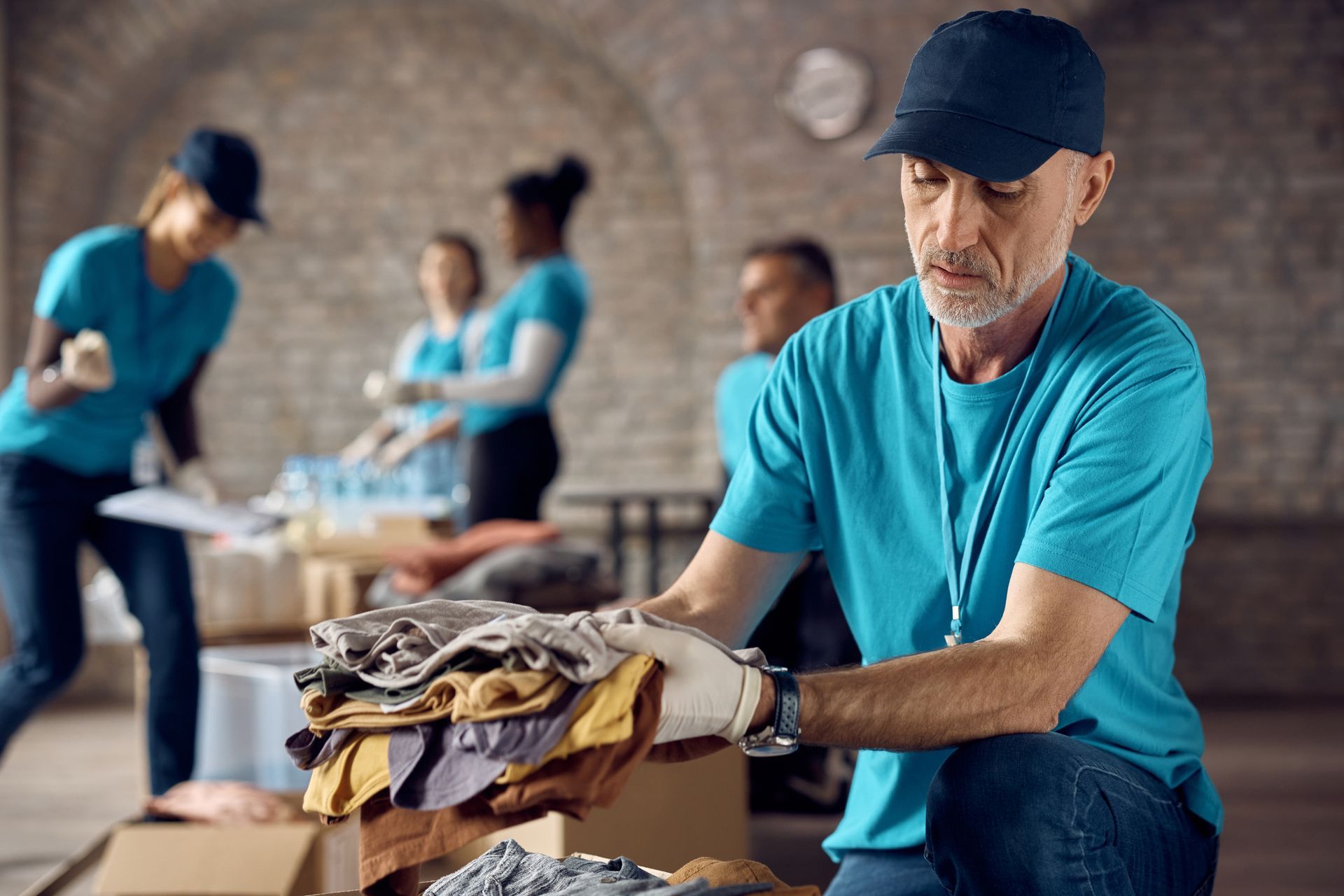 A man is sitting on the floor holding a pile of clothes.
