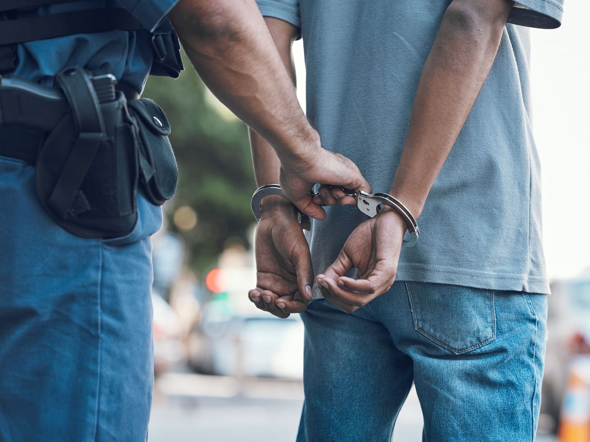 A cop holding a mans handcuffed hands behind his back