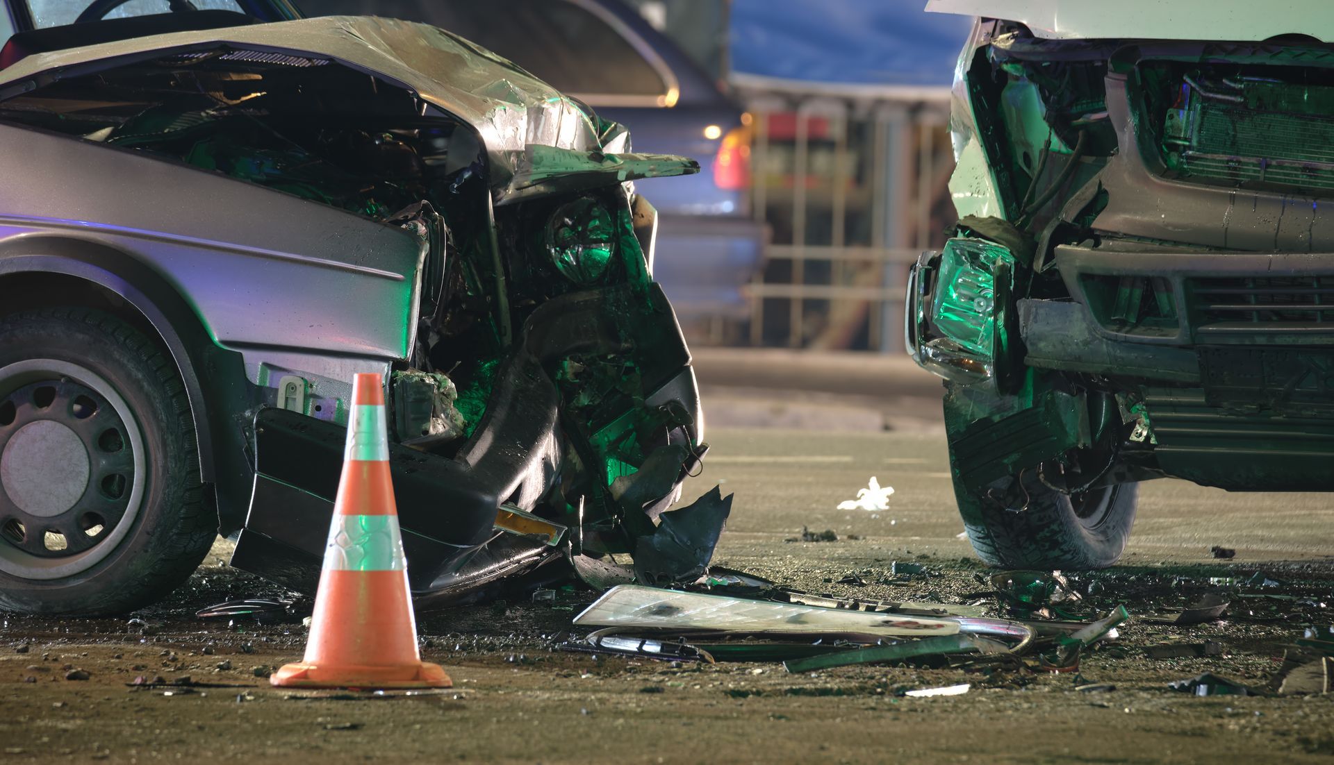 A car accident on a city street with a traffic cone in the foreground.