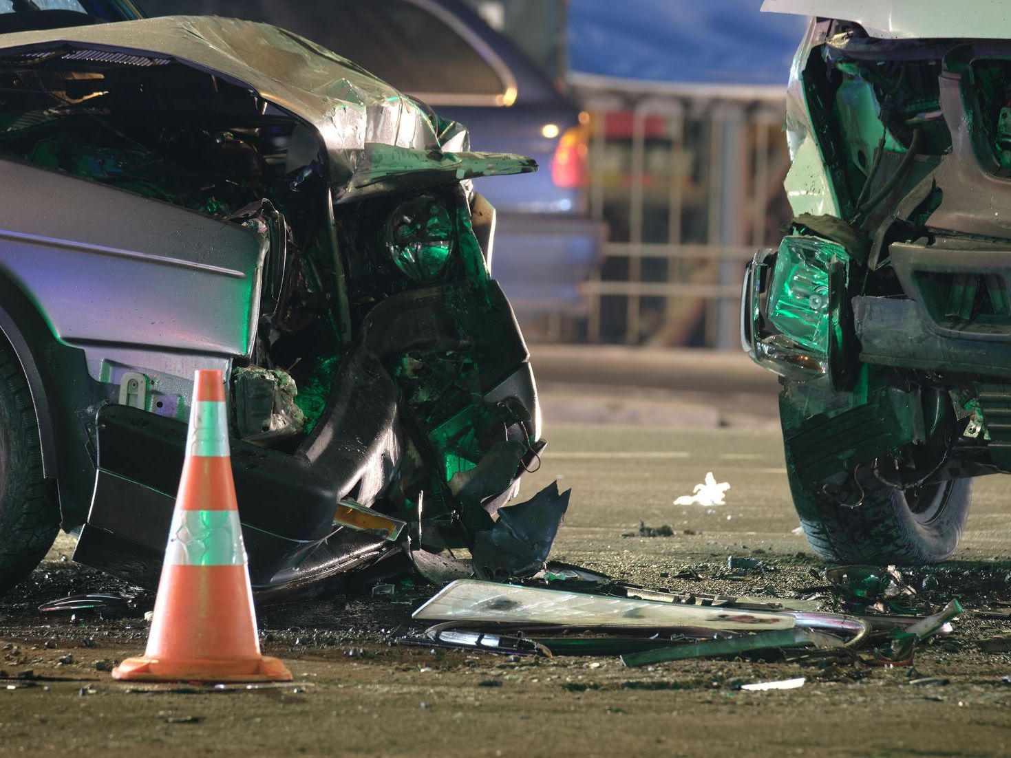 A car that has crashed into another car with a traffic cone in front of it