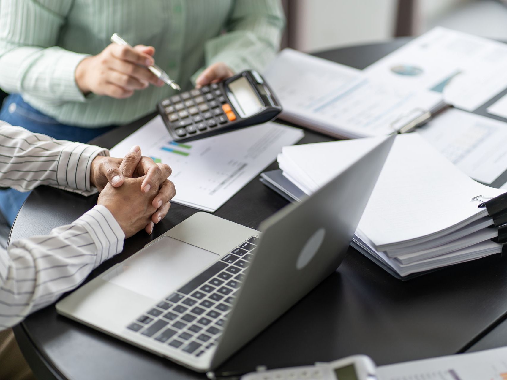 Two people are sitting at a table with a laptop and a calculator.