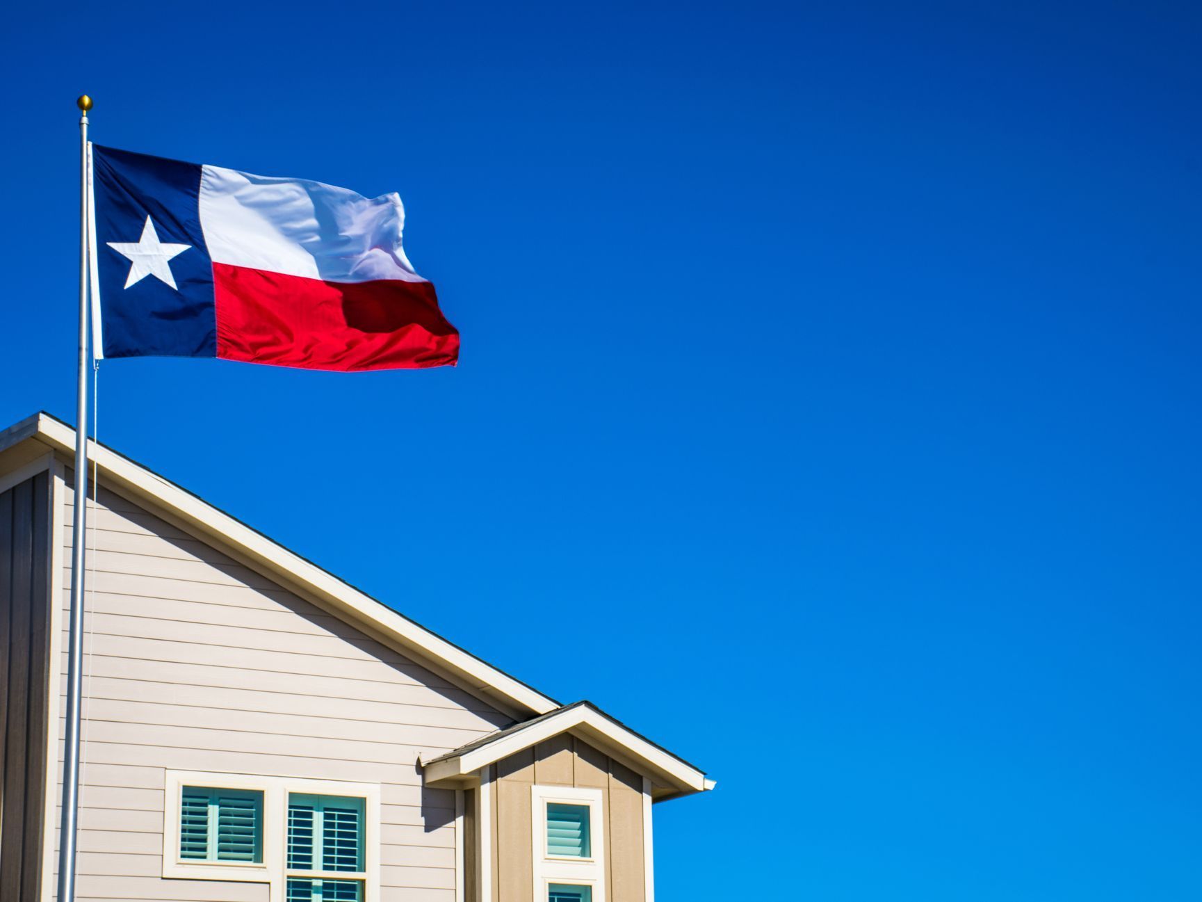 A texas flag is flying in front of a house