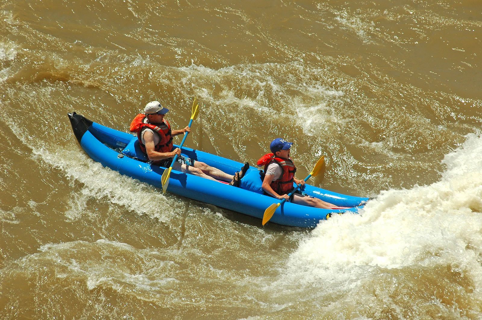 Two people are in a blue kayak on a river
