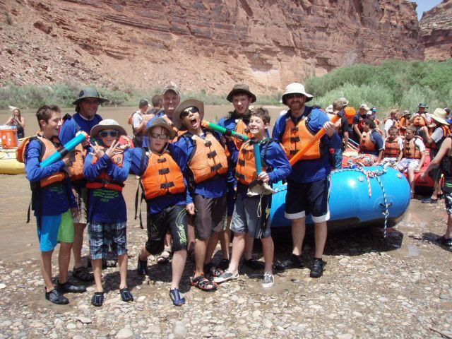 Young men standing in front of a blue boat.