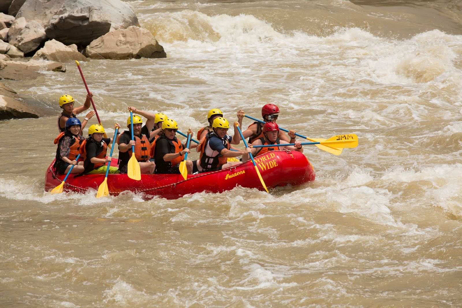 A group of people are rafting down a river in a red raft.