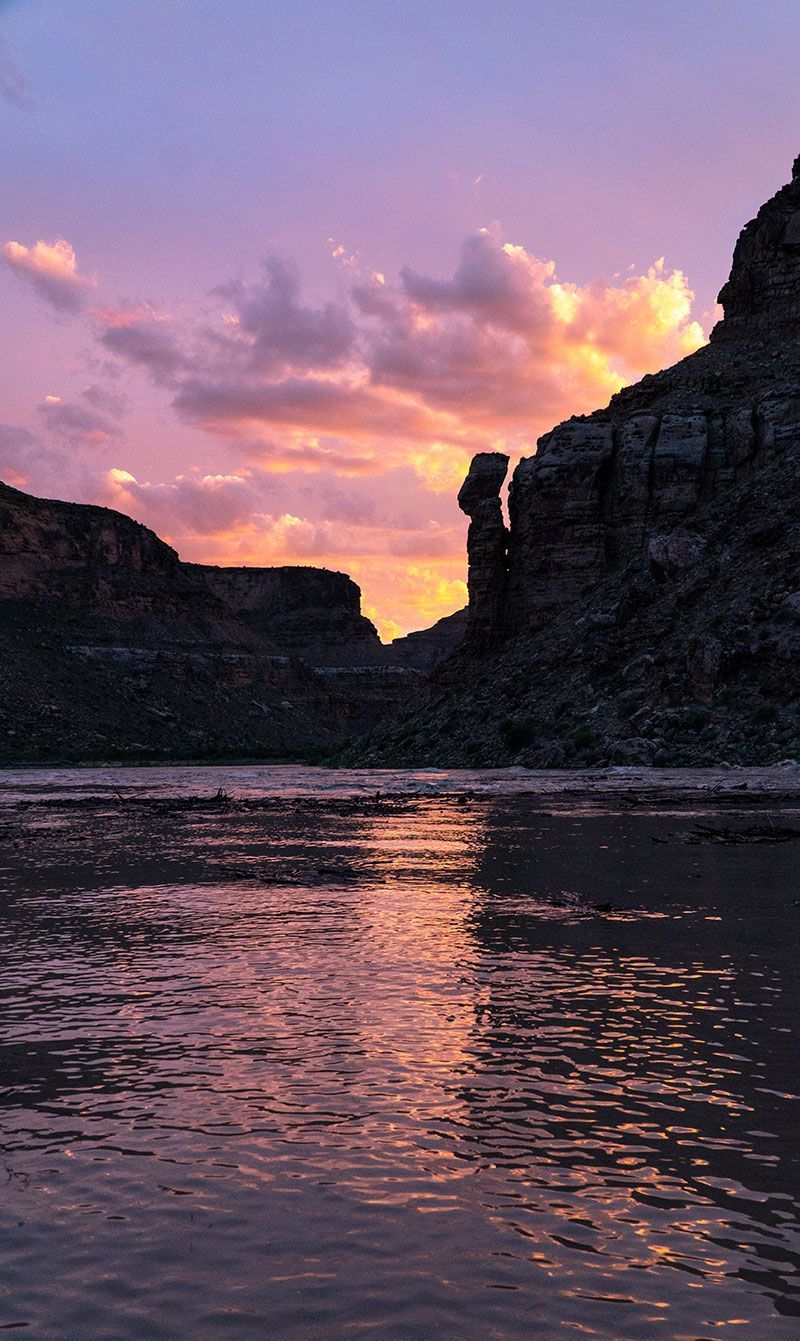 A river with a sunset in the background and a cliff in the foreground.