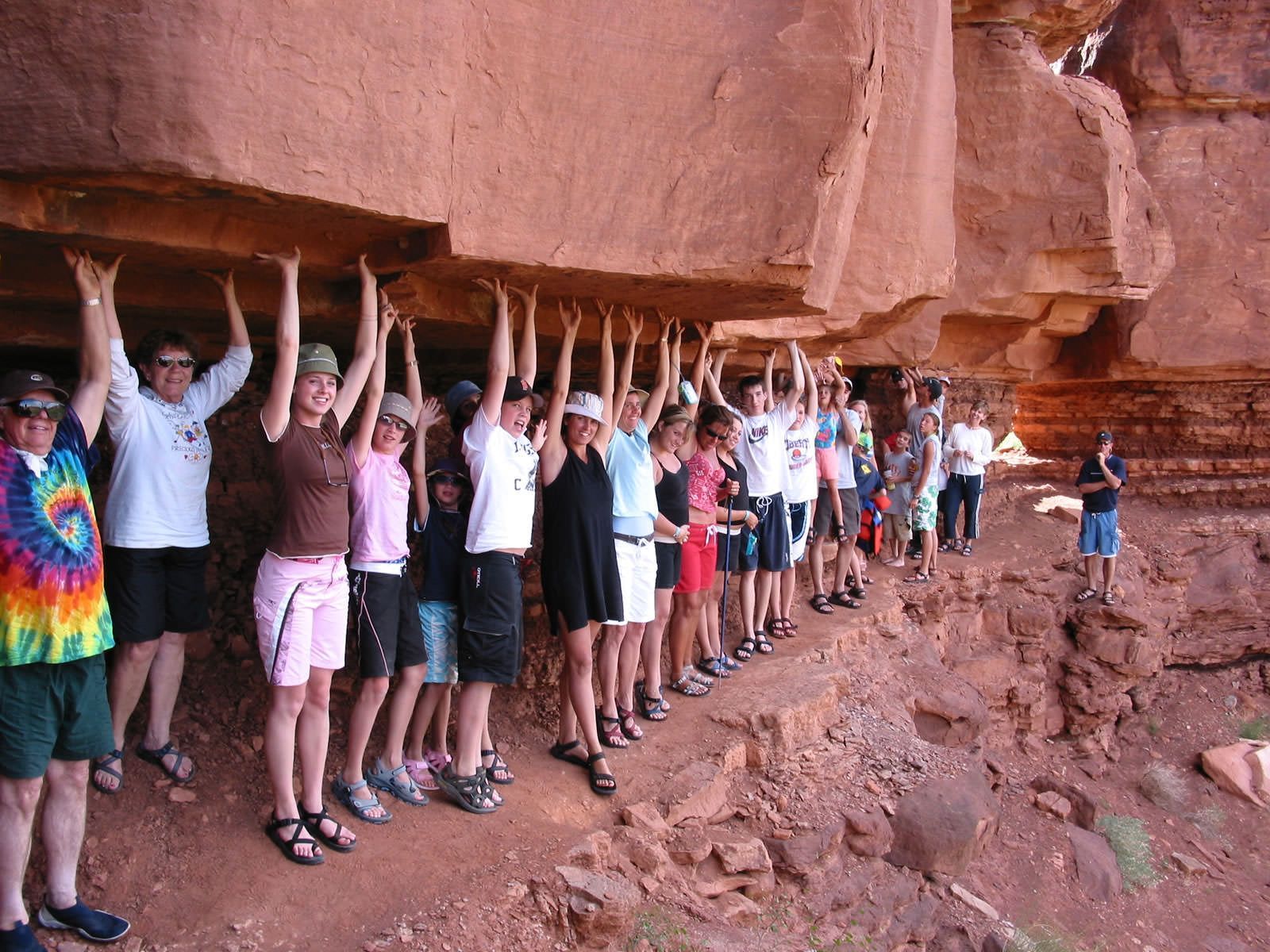A group of people standing under a rock with their hands up
