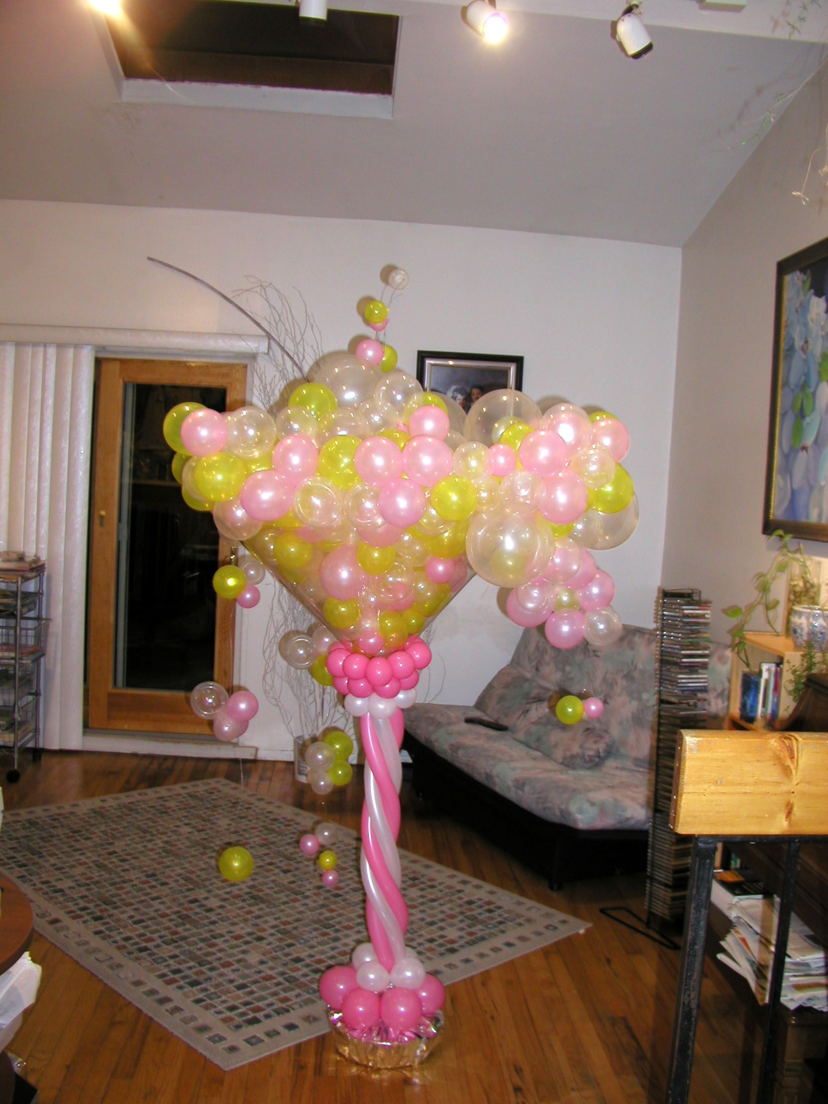 Balloon sculpture of a martini glass in pink, yellow, and clear.