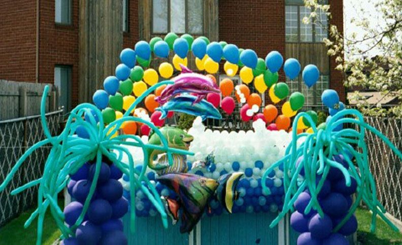 Colorful balloon archway shaped like an ocean scene, featuring dolphins, rainbow, and wave-like structures.