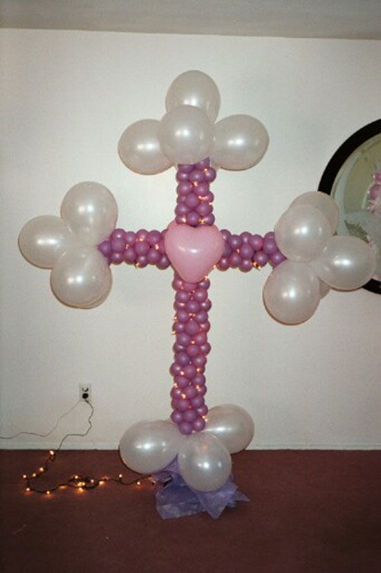 Balloon cross decoration with white and purple balloons, and a pink heart.