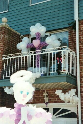 A balcony decorated with balloon angels and a cross, in white and purple.