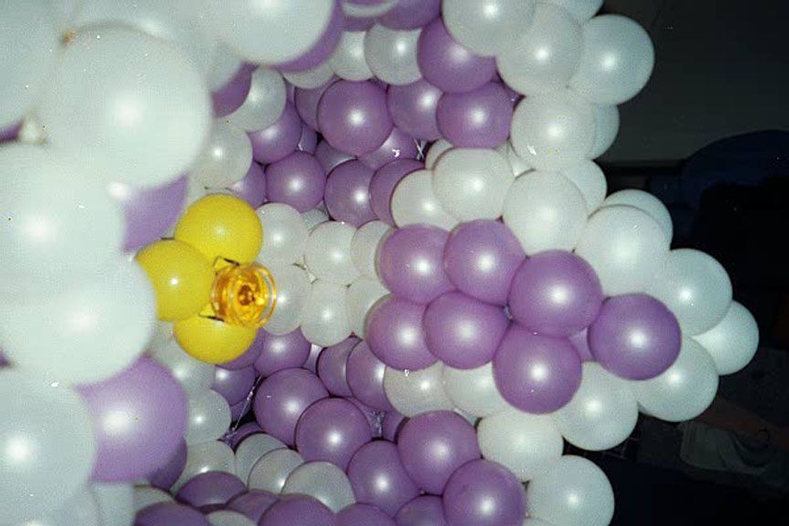 White and purple balloon tunnel with yellow flower accent.