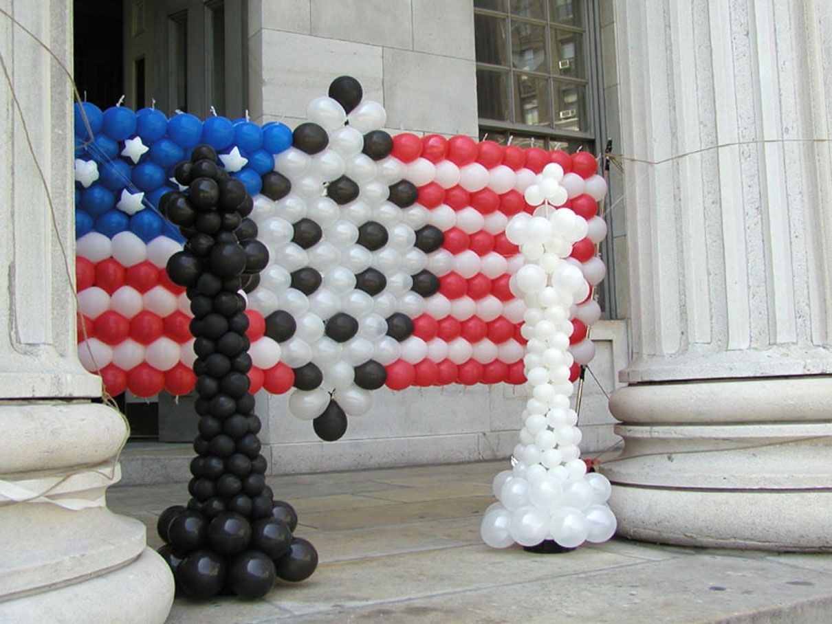 Chess pieces made of balloons, in front of a balloon American flag on a building's steps.