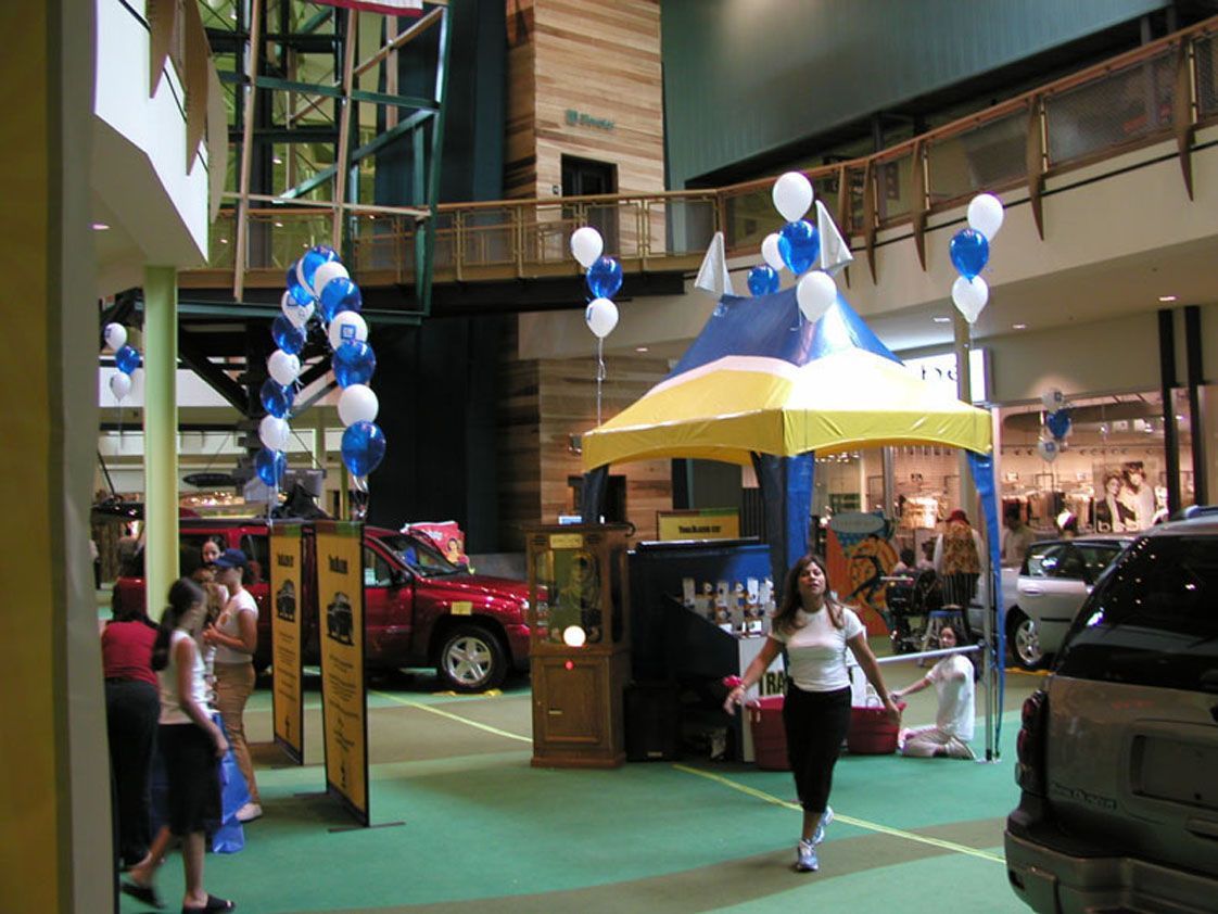 Indoor event with cars, a tent, balloons, and people.