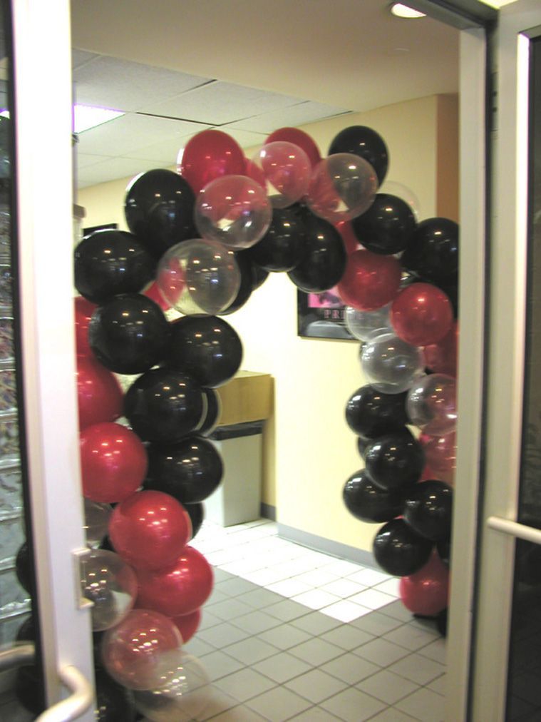 Doorway arch decorated with red, black, and clear balloons.