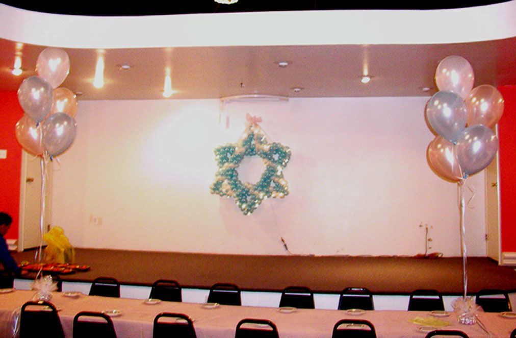 Room decorated for a party, with balloons and a star-shaped ornament hanging on a white wall.