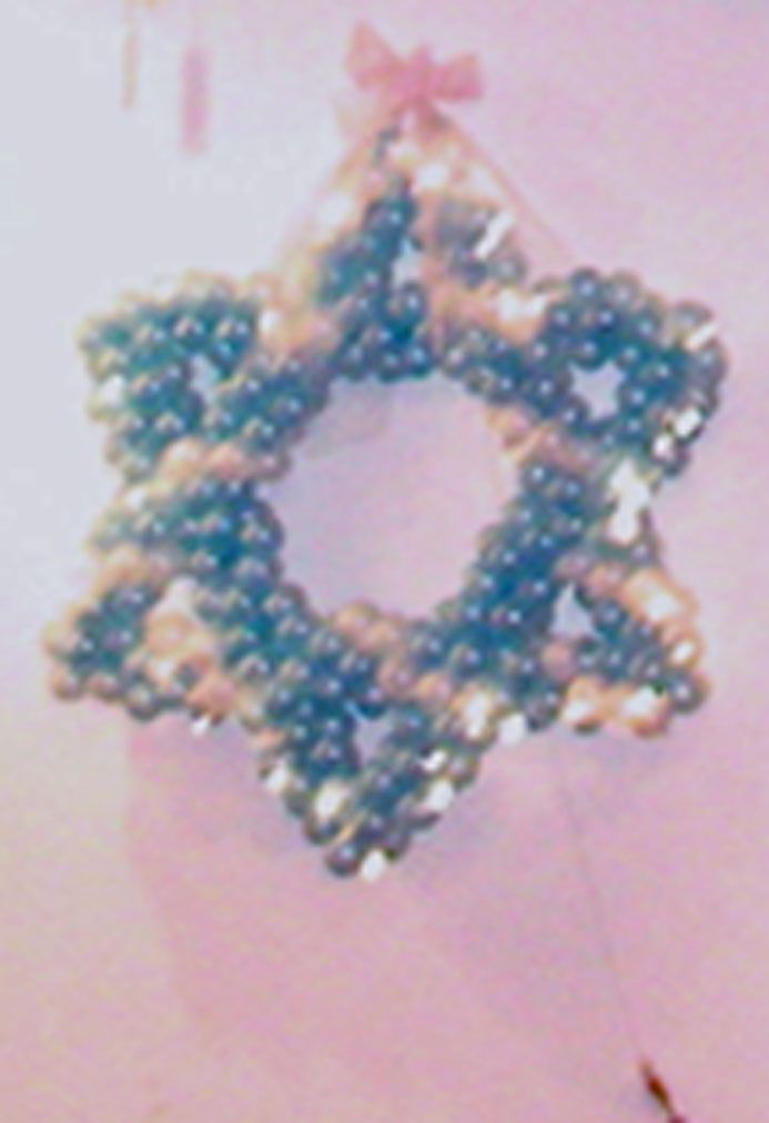 Star of David made of green and tan beads, hanging from a pink bow.
