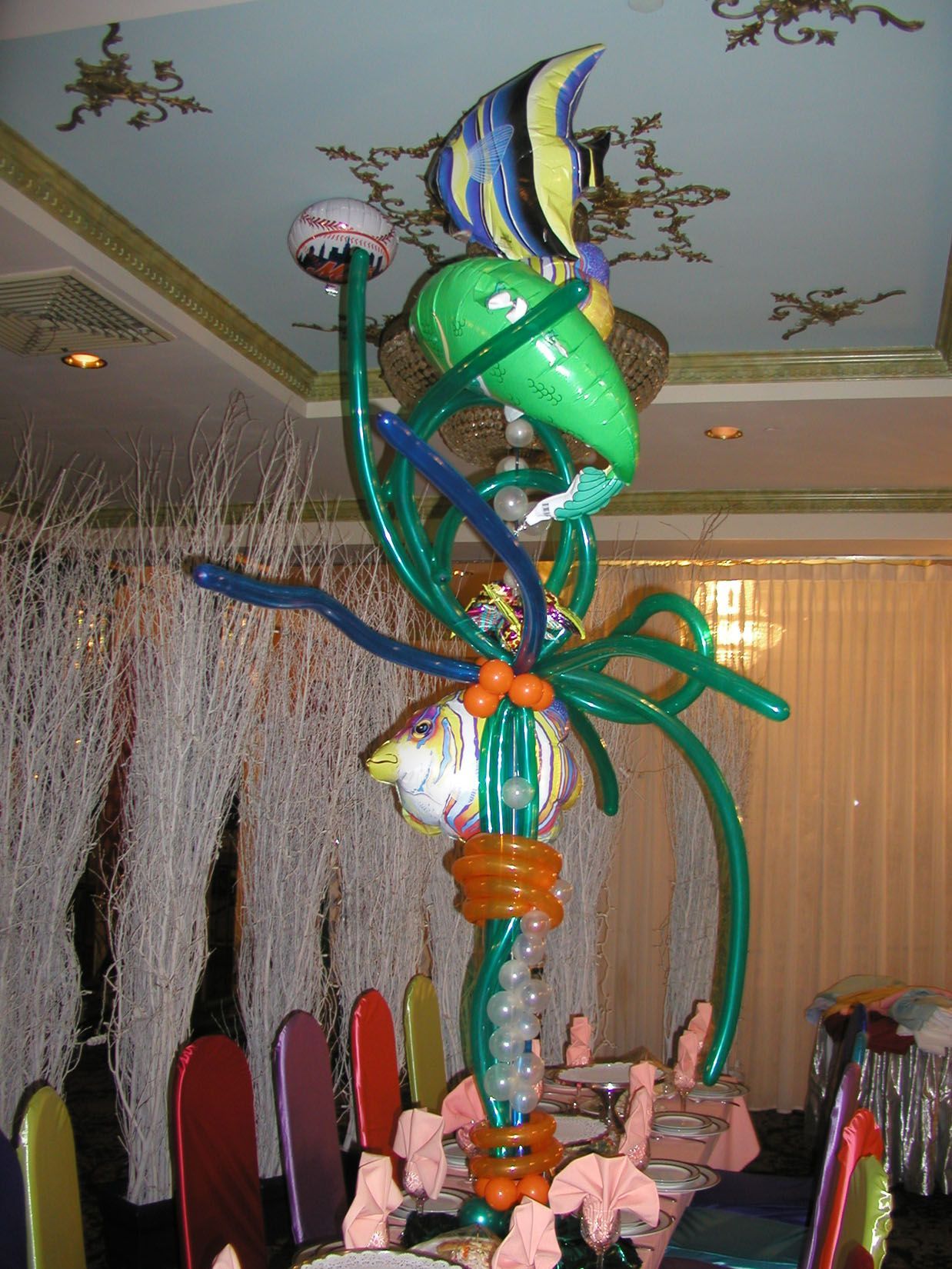 Balloon sculpture of various aquatic animals, including fish, atop a table in a decorated room.