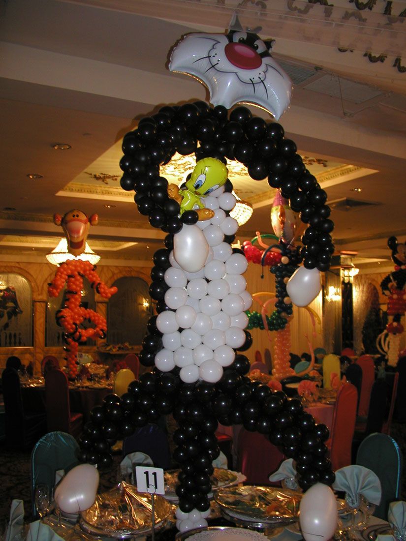 A large balloon sculpture of Sylvester the Cat chasing Tweety Bird at a party.