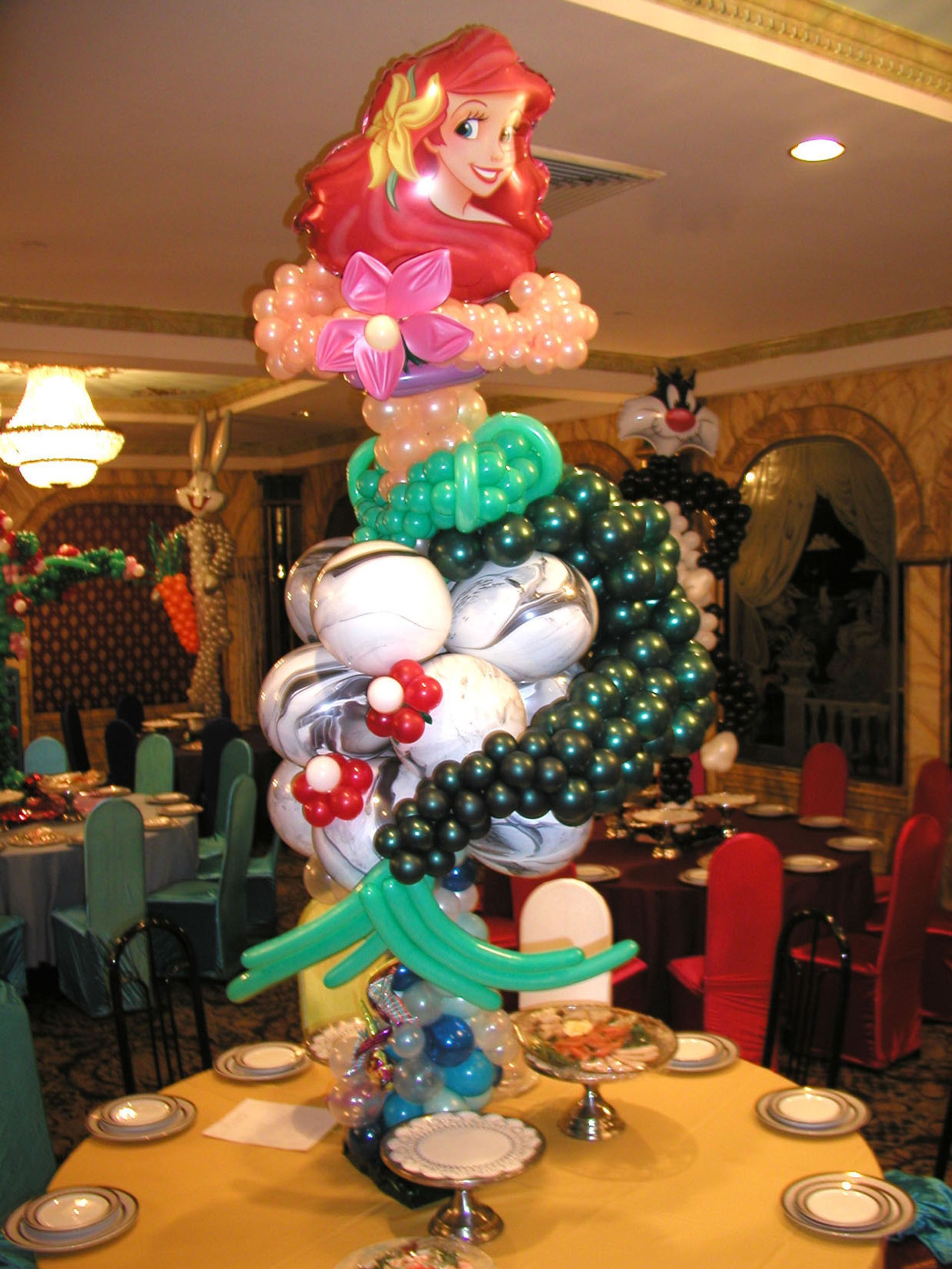 Ariel balloon sculpture centerpiece on a table in a decorated dining hall.