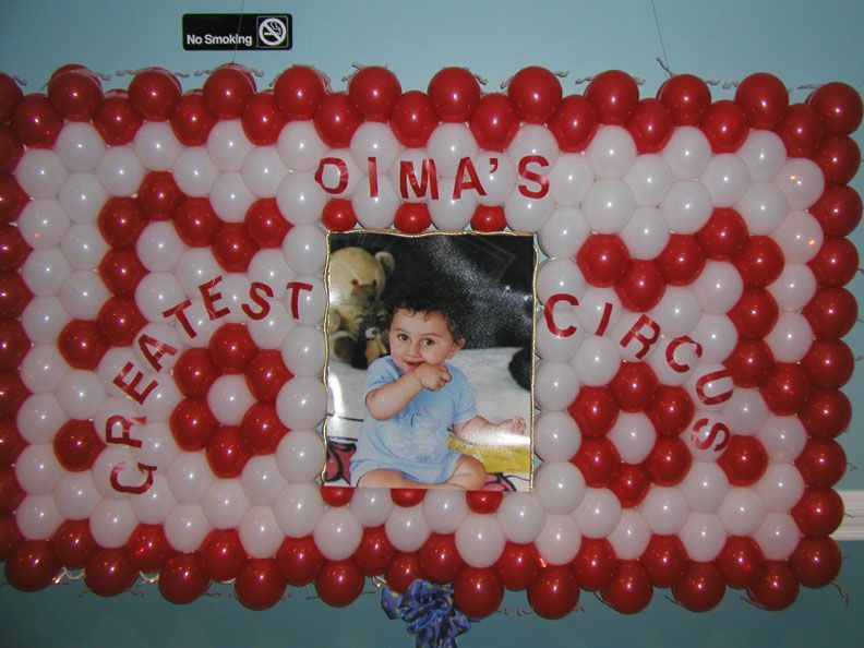 Dima's Greatest Circus balloon display with a photo of a baby; red and white balloons.