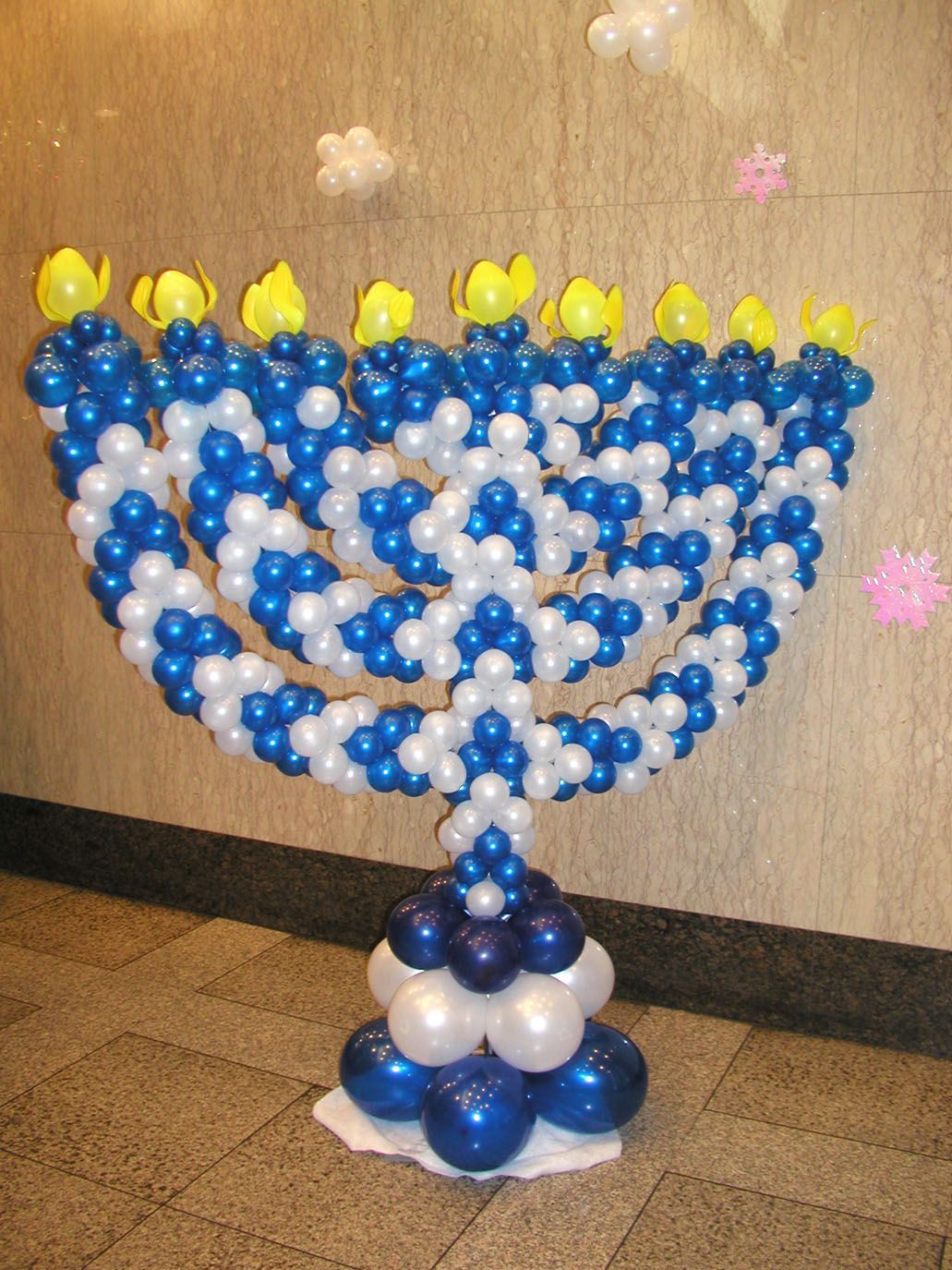 Balloon menorah made of blue, white, and yellow balloons.