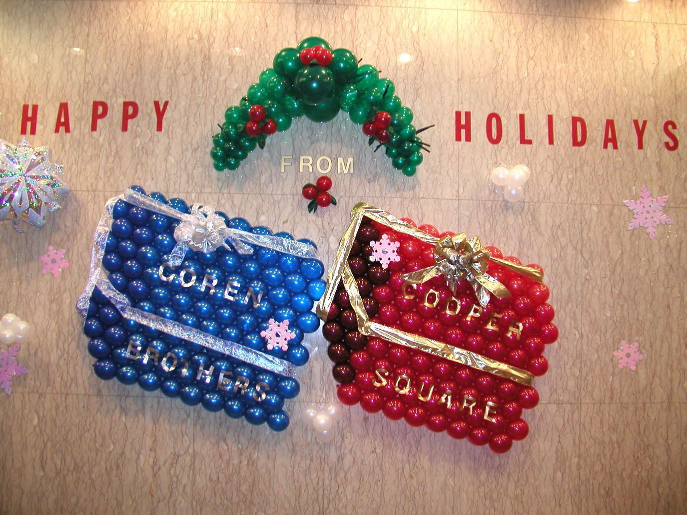 Holiday balloon display: Blue and red boxes with text, green garland, and 