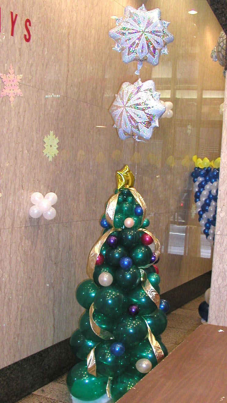 Christmas window display featuring a balloon Christmas tree with ornaments and snowflake balloons.