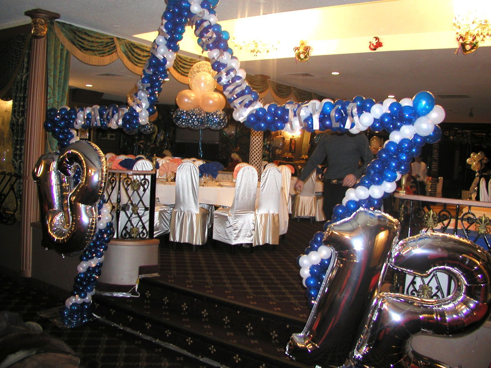 Birthday celebration in a restaurant, blue and white balloon arch with silver 