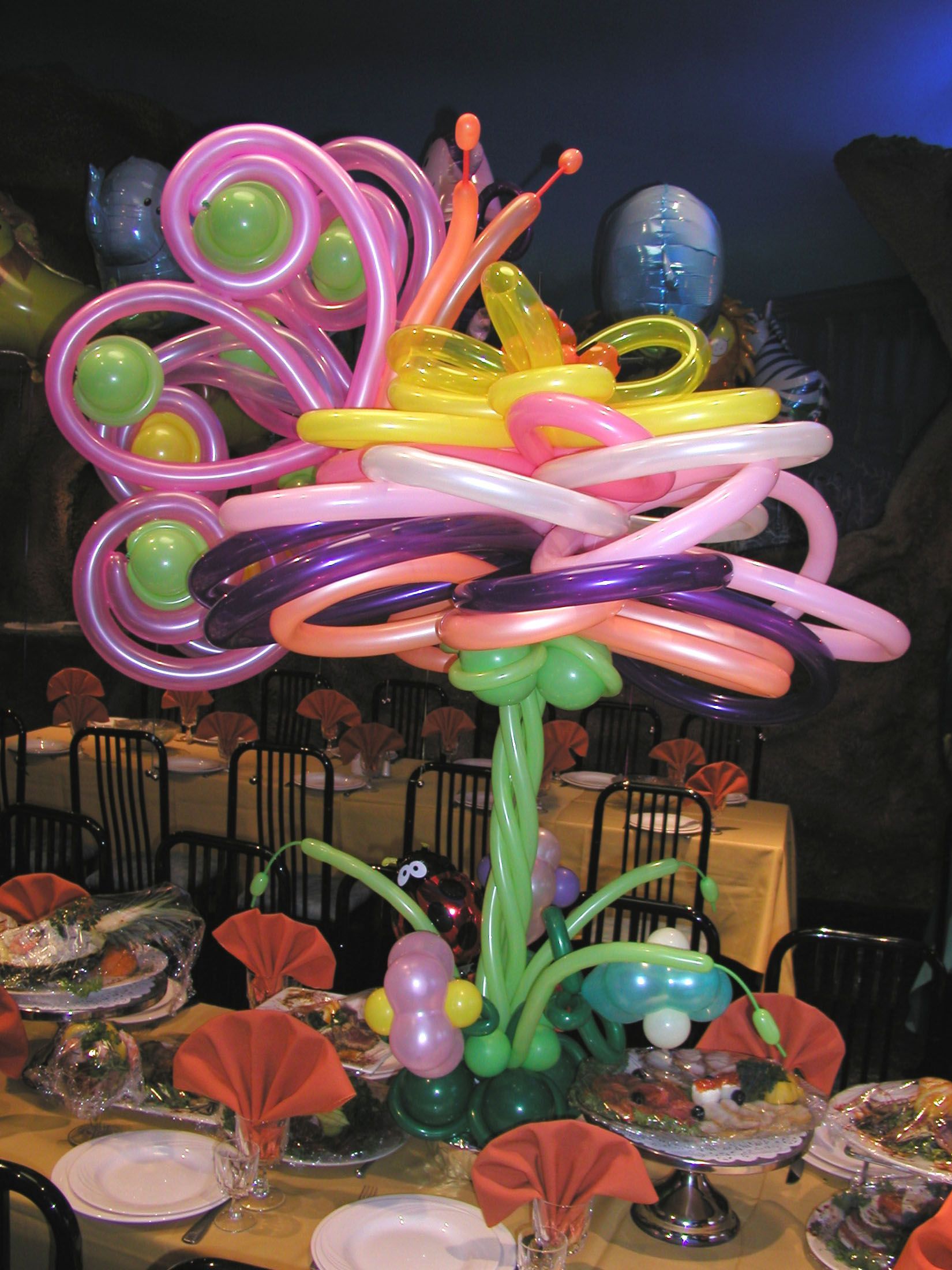 Colorful balloon flower centerpiece on a table, with dining area in the background.
