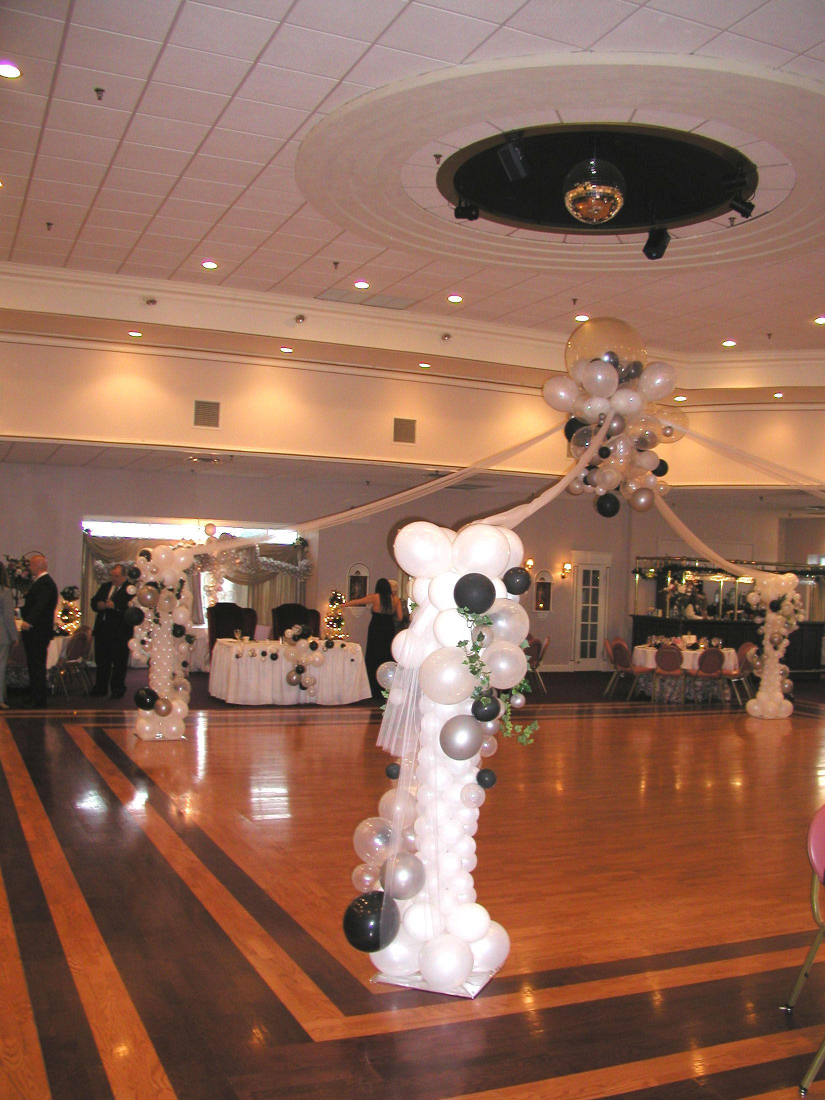 Ballroom with a balloon column and a disco ball; white and black decor.