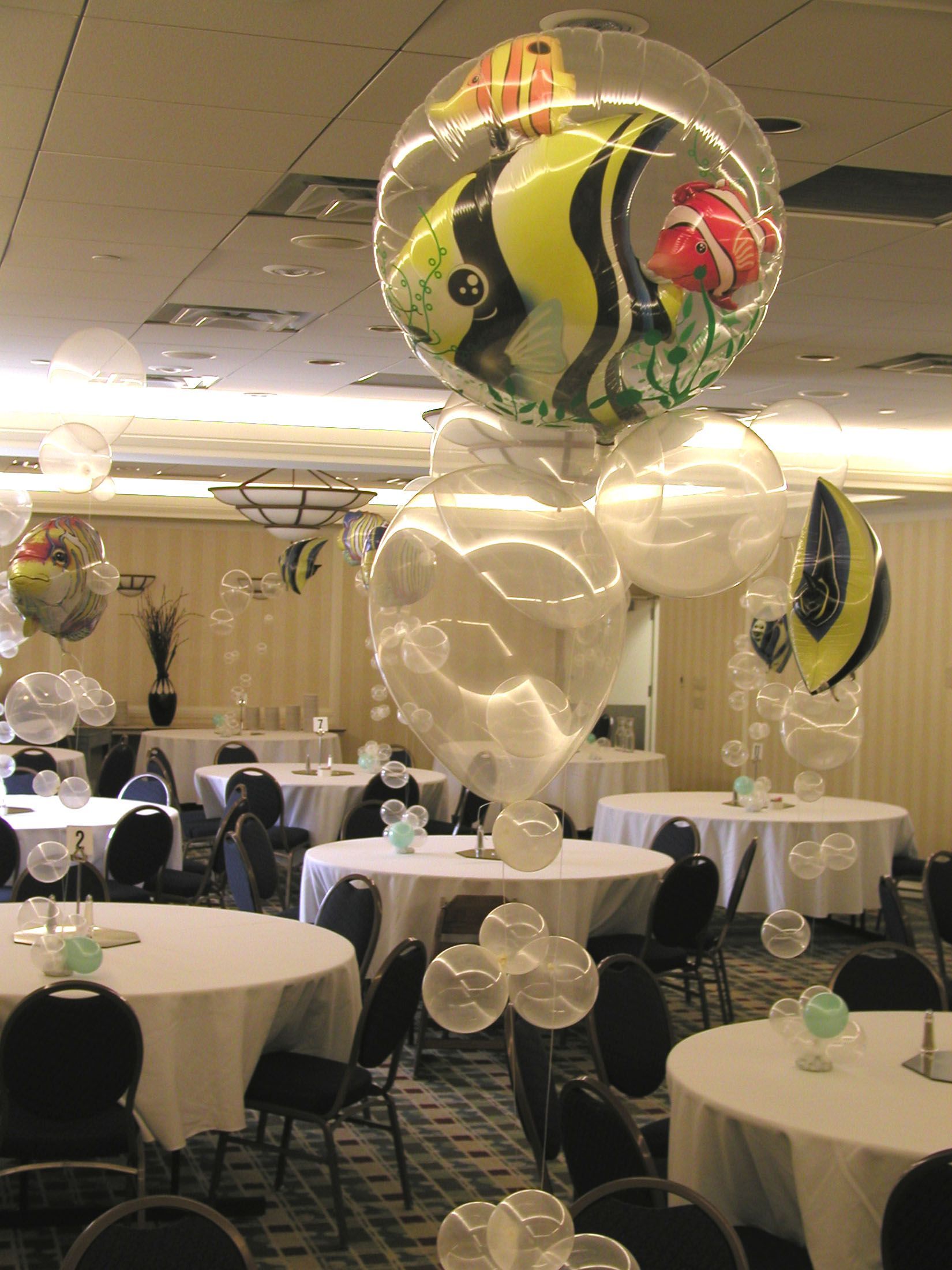Room decorated with clear balloons, including an elaborate fish-themed balloon centerpiece.