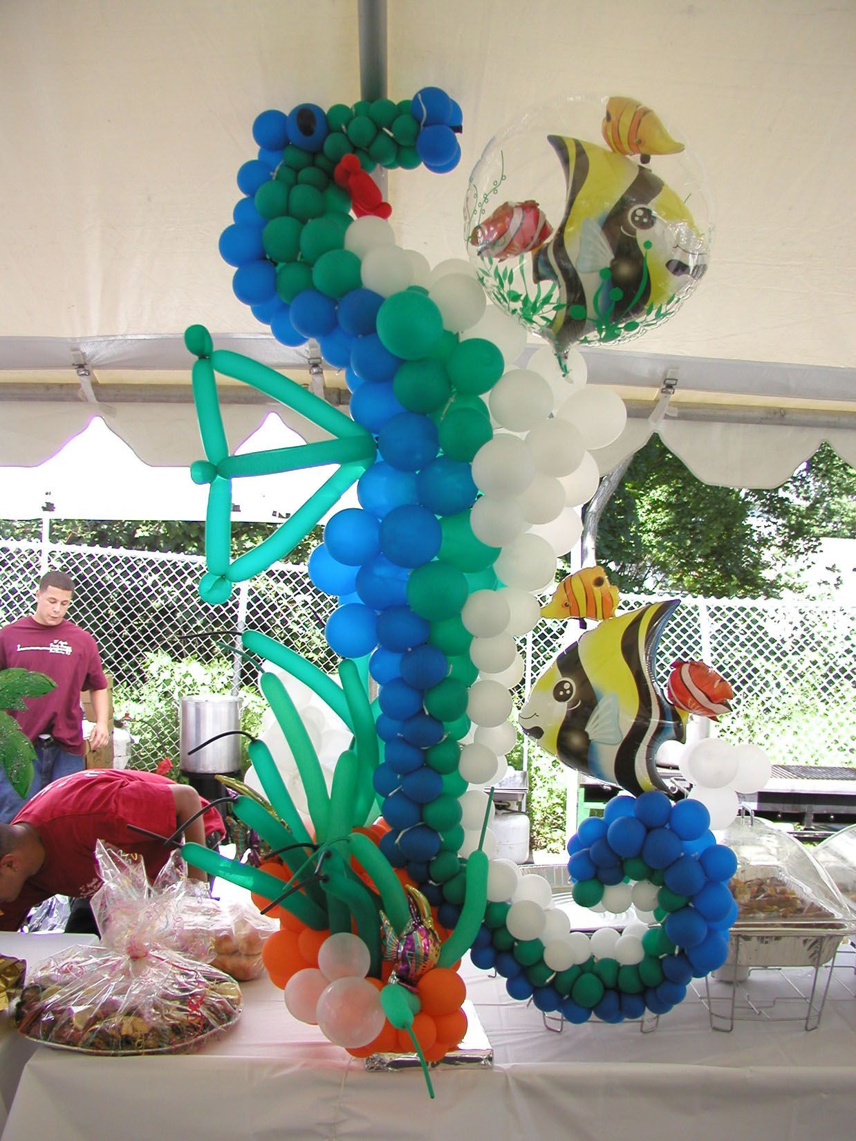 A whimsical seahorse balloon sculpture with fish balloons and a table setting.