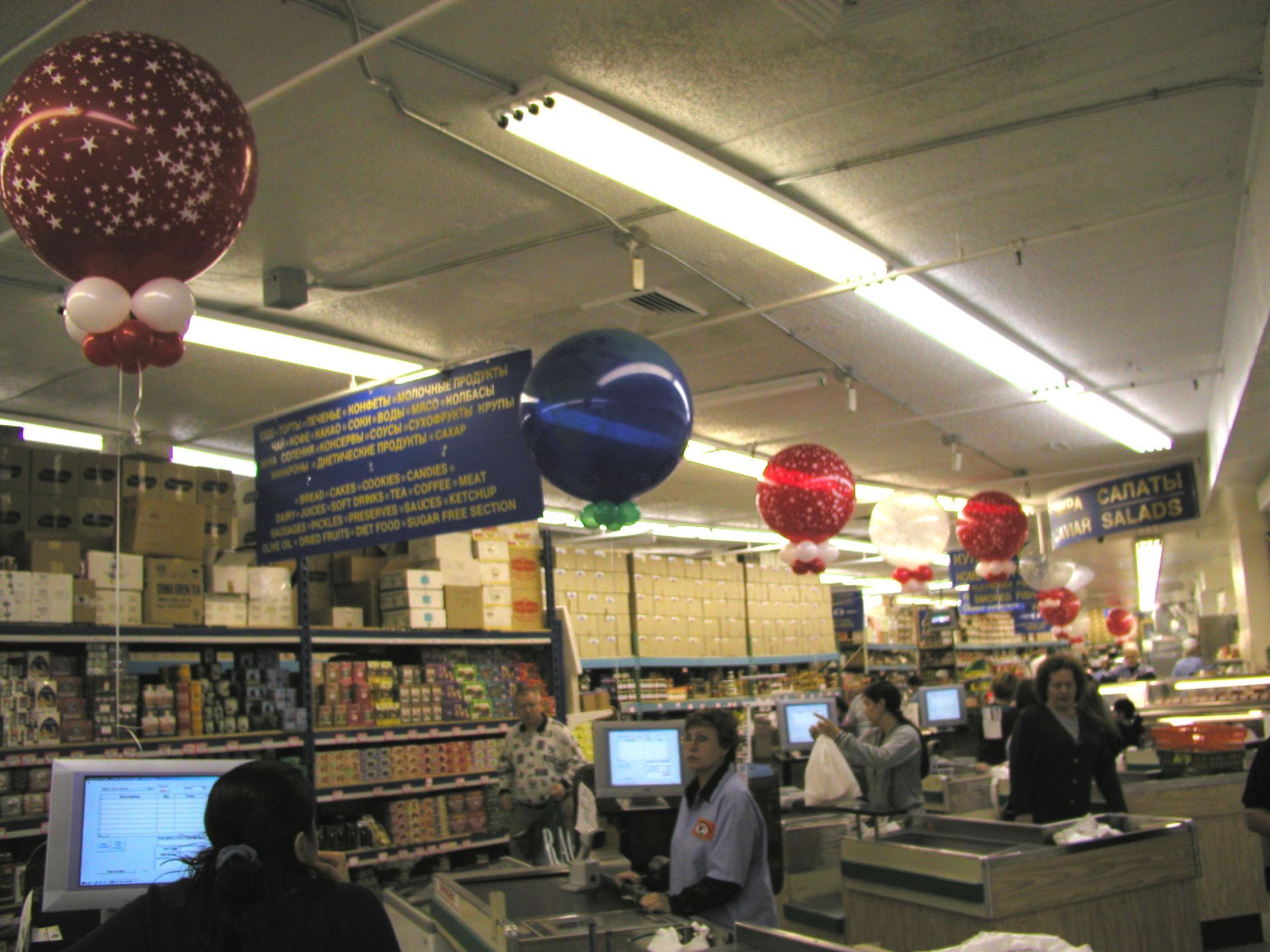 Grocery store interior with balloons and cashiers at checkouts.