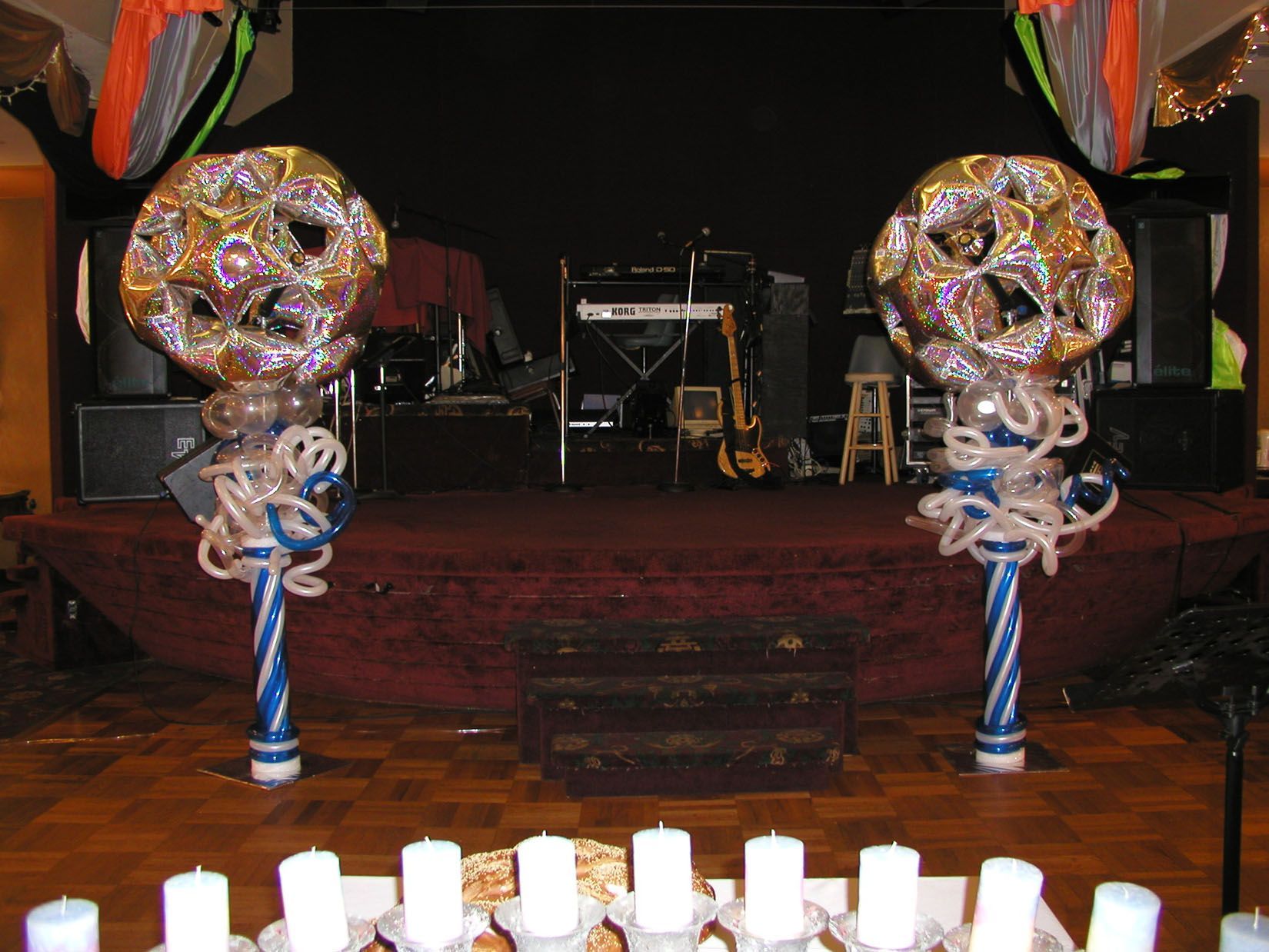 Stage with band equipment. Two large decorated spheres flank the stage. Candles in foreground.