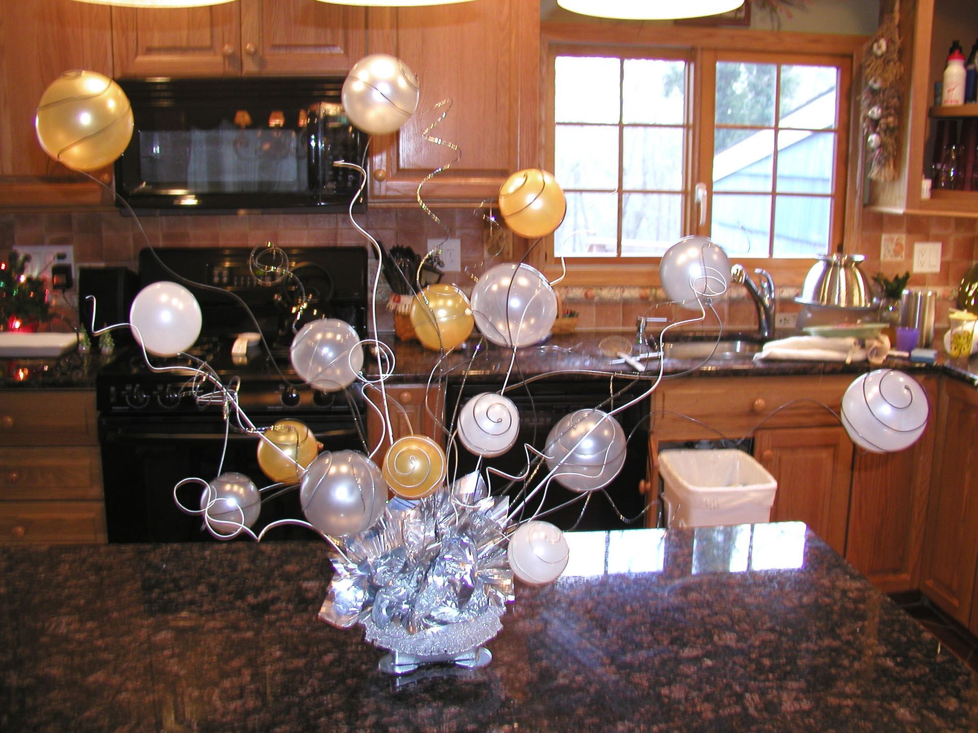 Kitchen with countertop centerpiece of silver and gold balloons on wire stems.