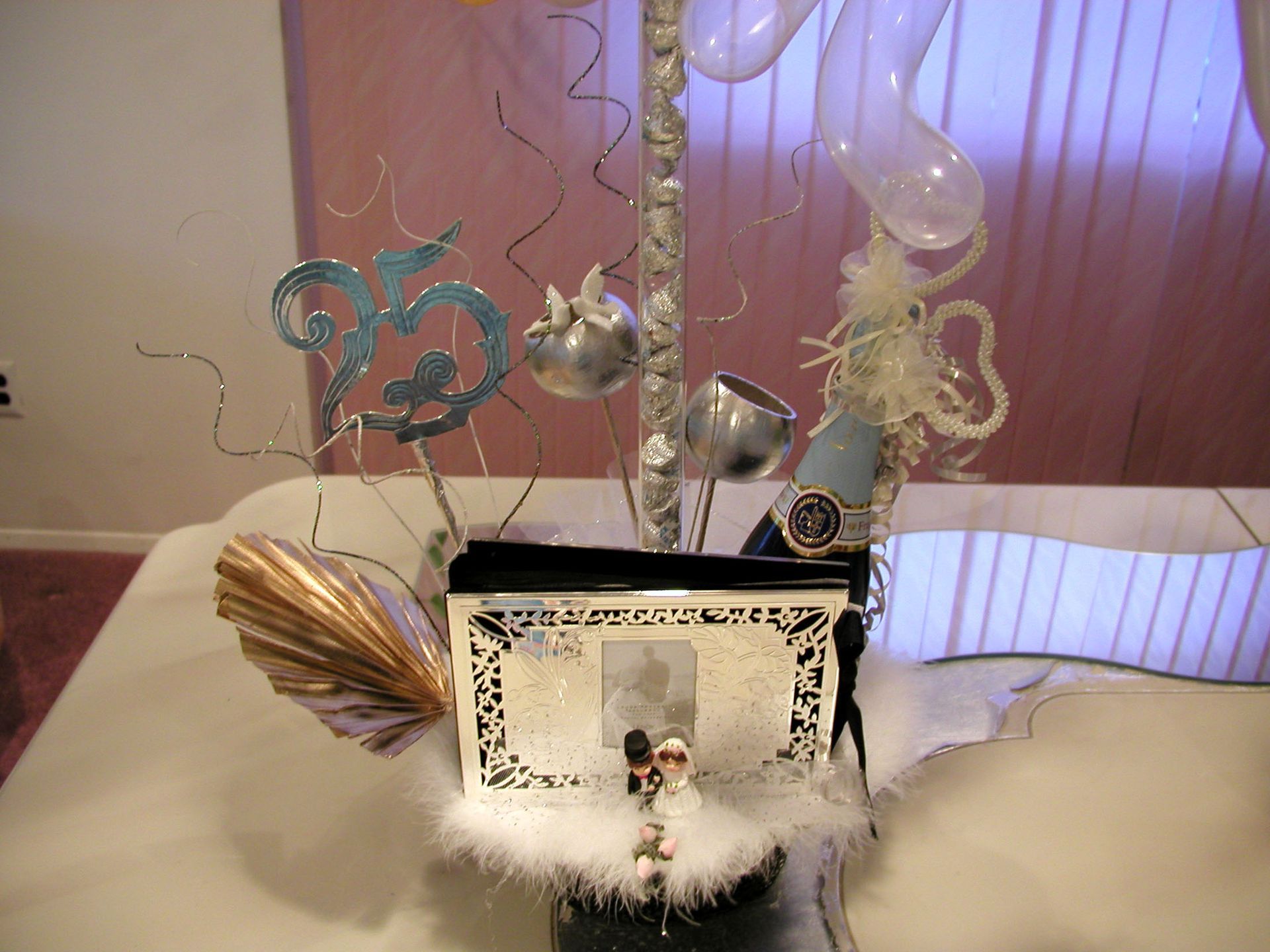Centerpiece with figurines, silver accents, and balloons, likely for a celebration.