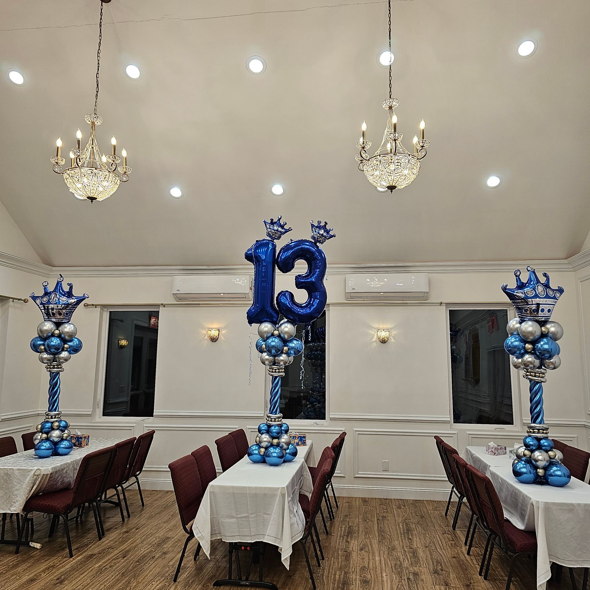 Party room decorated with blue and silver balloon centerpieces for a thirteenth birthday.