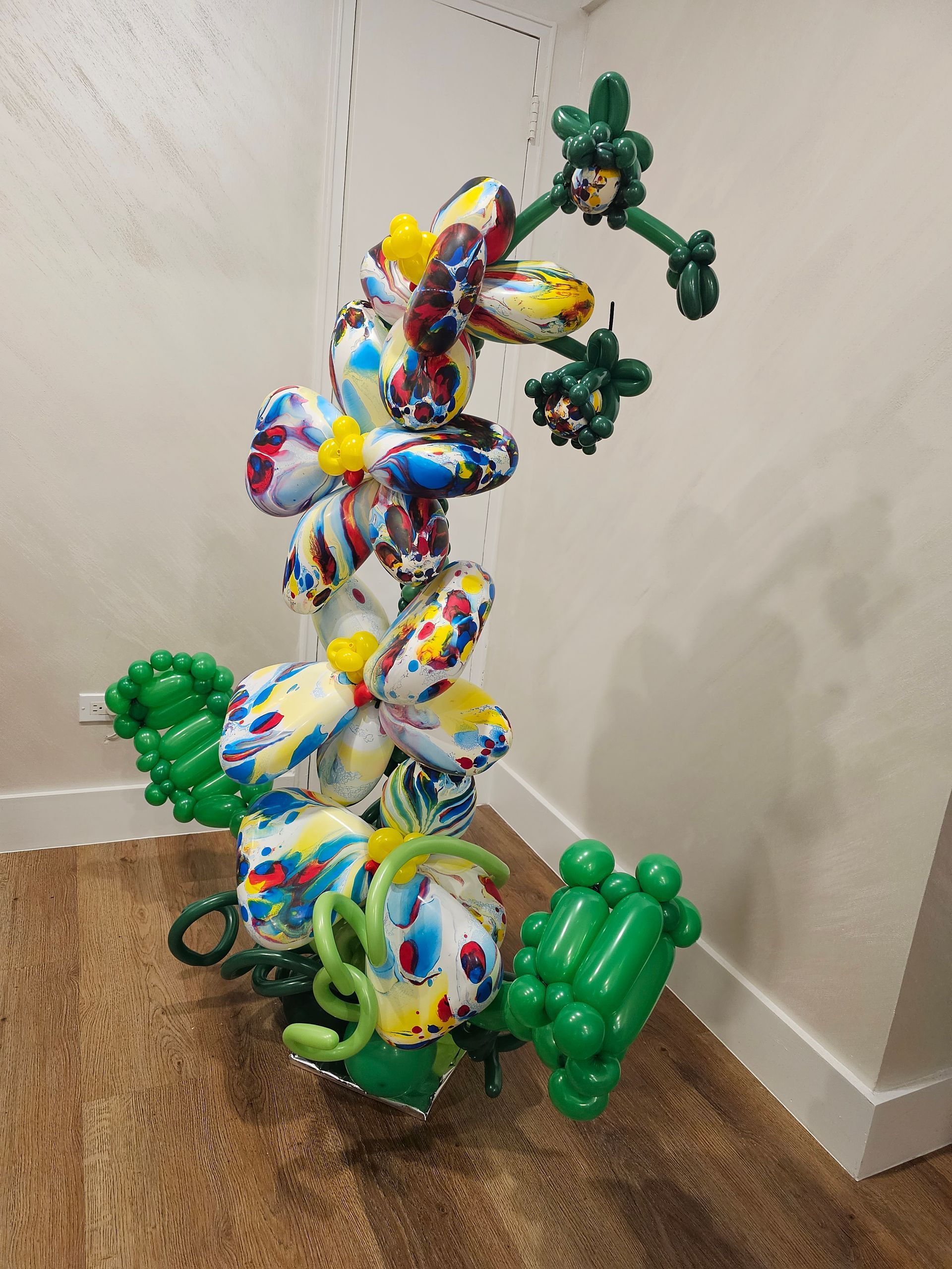 Balloon sculpture: Colorful floral design with green leaves, stems, and smaller flower clusters.