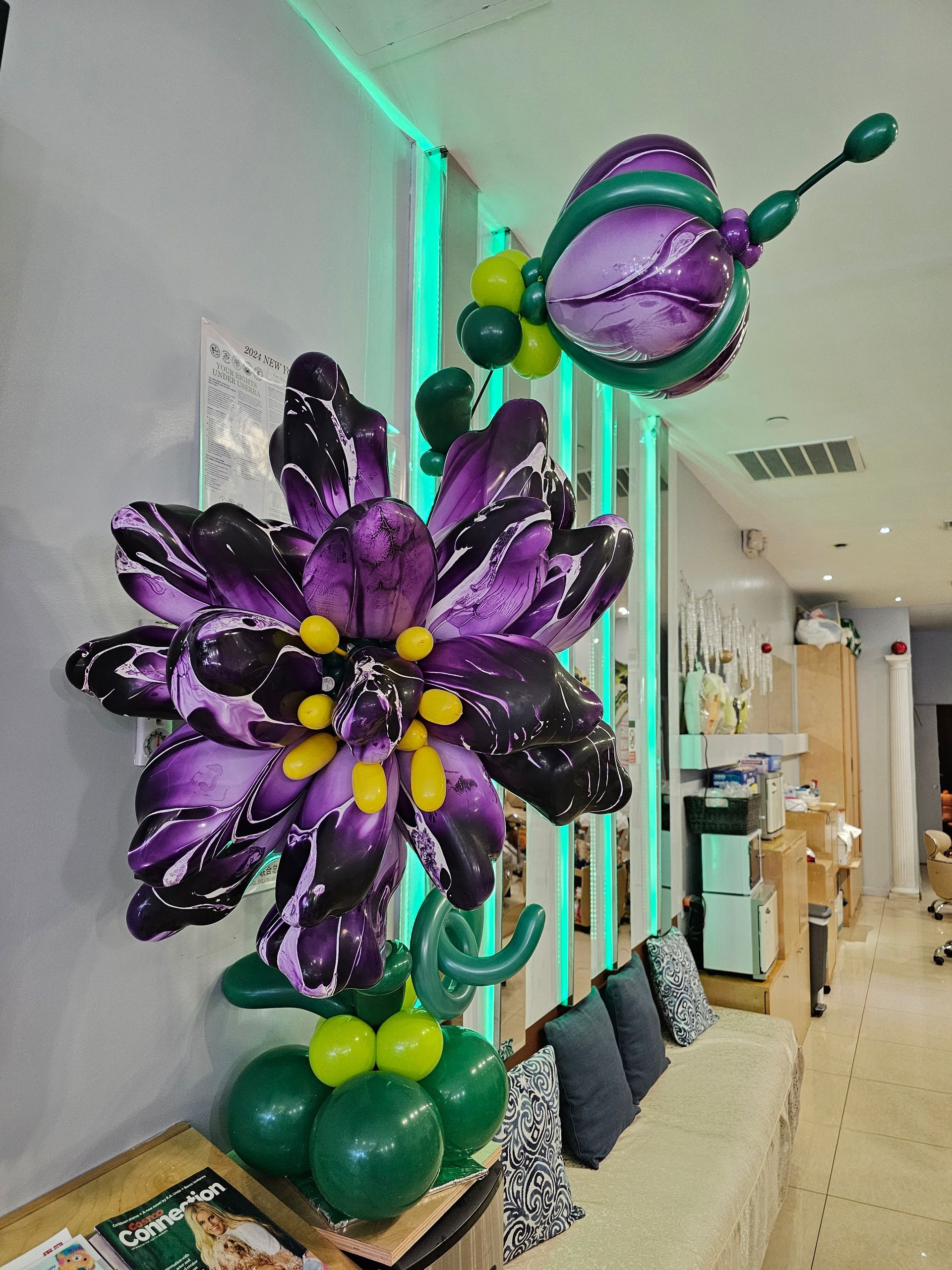 Balloon flower sculpture: large purple flower and butterfly, green base and stem, indoors.